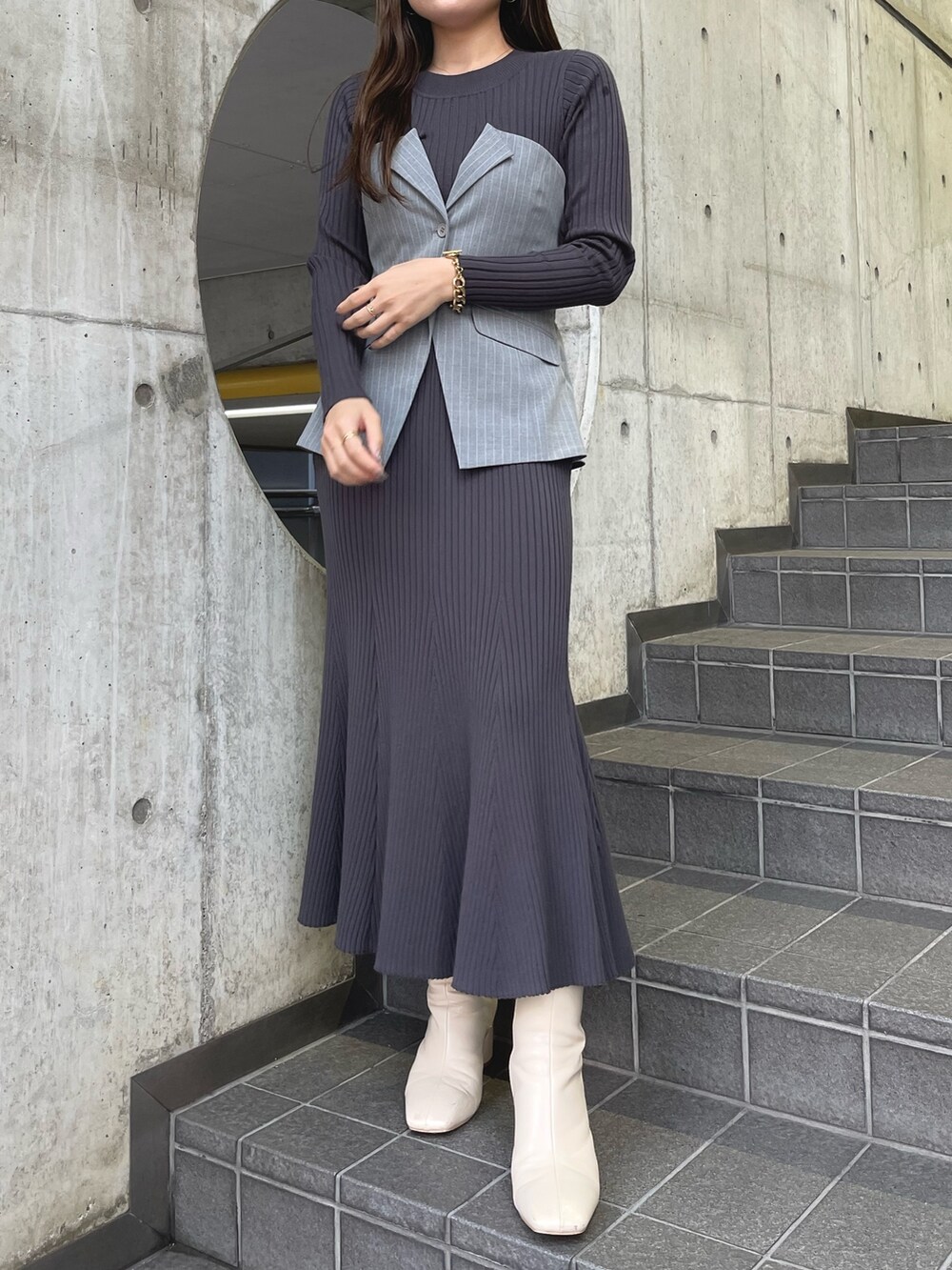 グレー系のワンピース、ホワイト系のブーツを着用したレディースの冬コーディネートの2枚目の写真