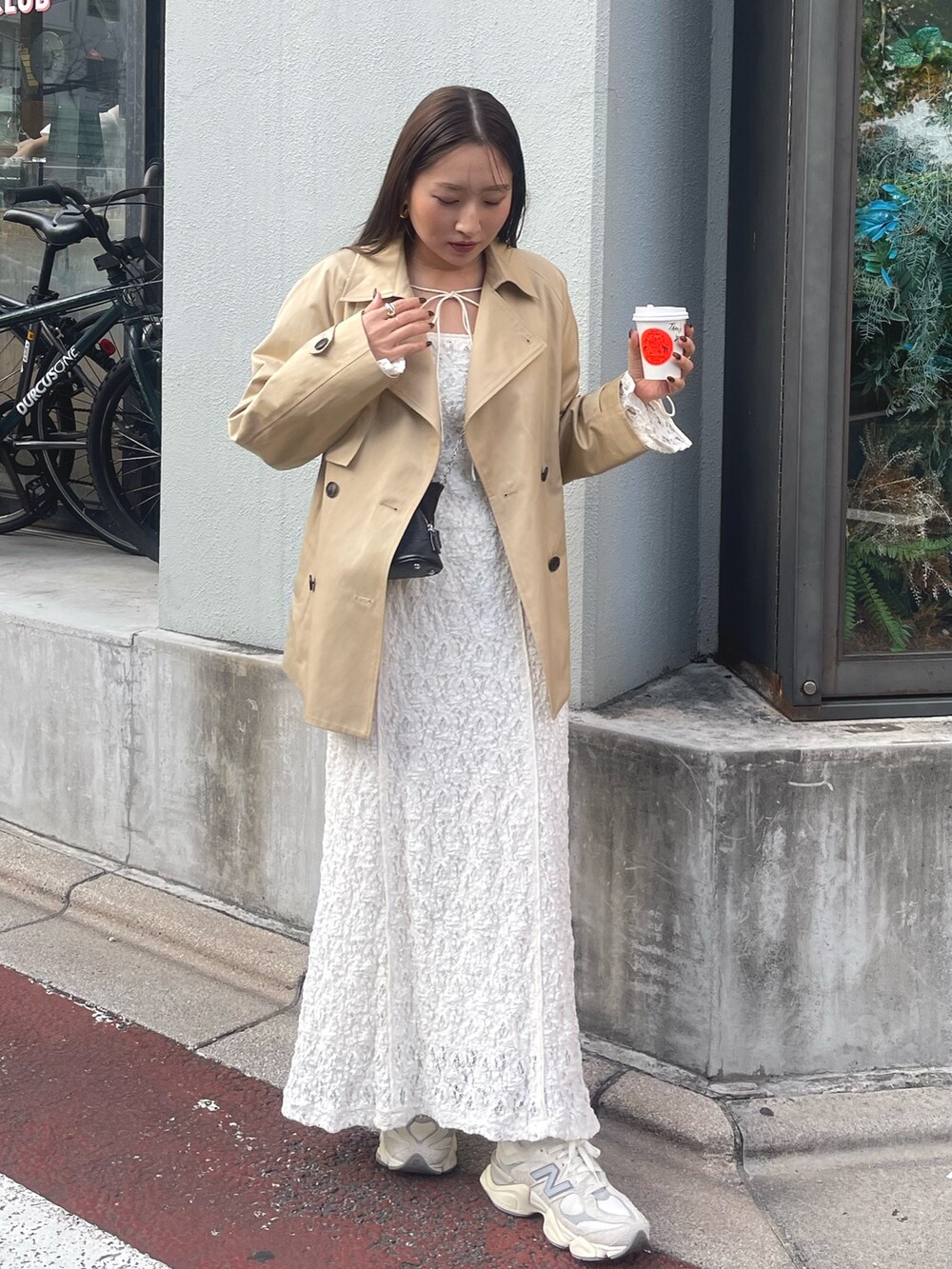 ホワイト系のワンピース、ベージュ系のトレンチコート、ゴールド系のピアス（両耳用）を着用したレディースの冬コーディネートの3枚目の写真