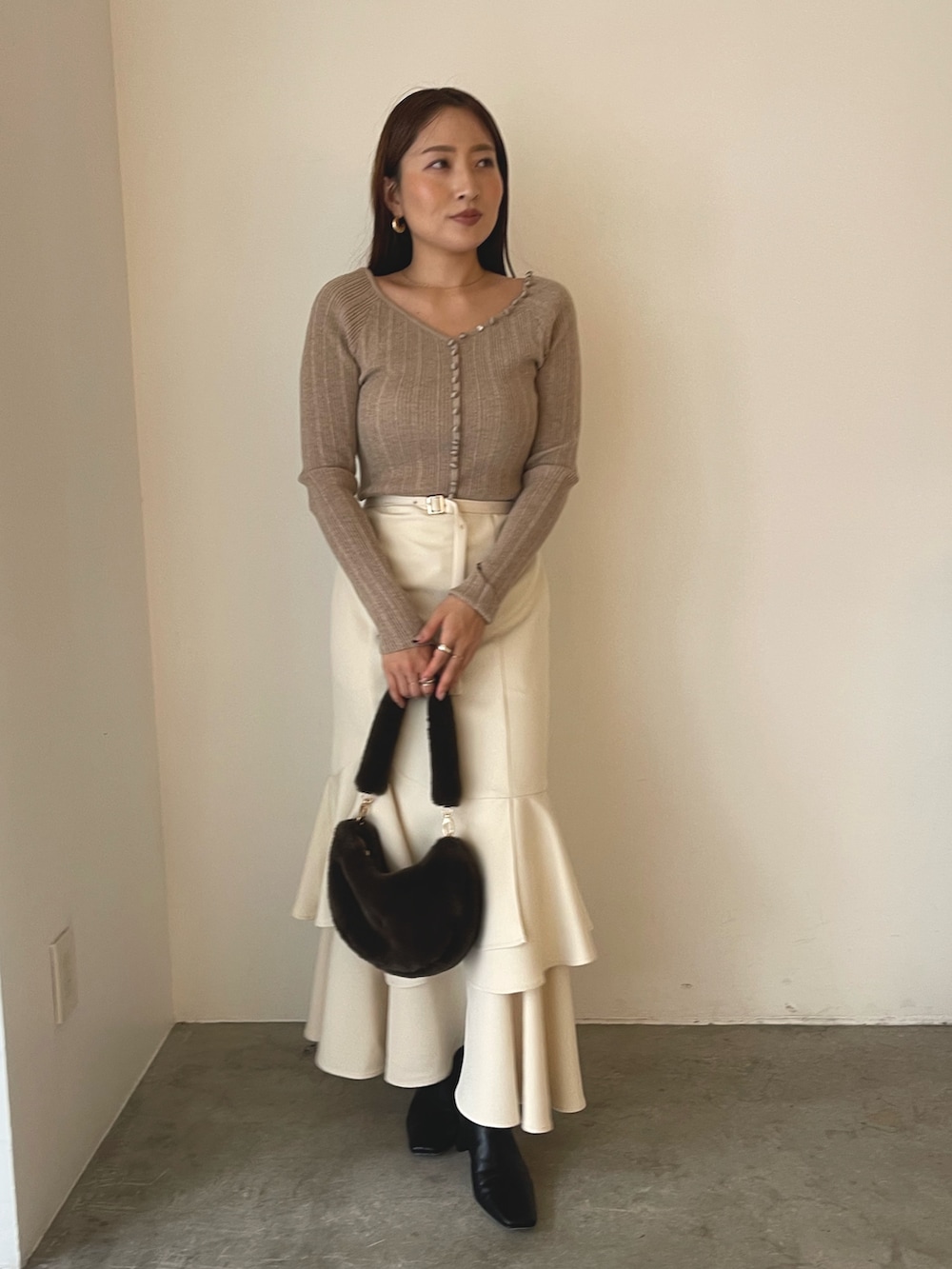 ブラウン系のショルダーバッグ、ブラック系のブーツ、ベージュ系のワンピースを着用したレディースの冬コーディネートの3枚目の写真