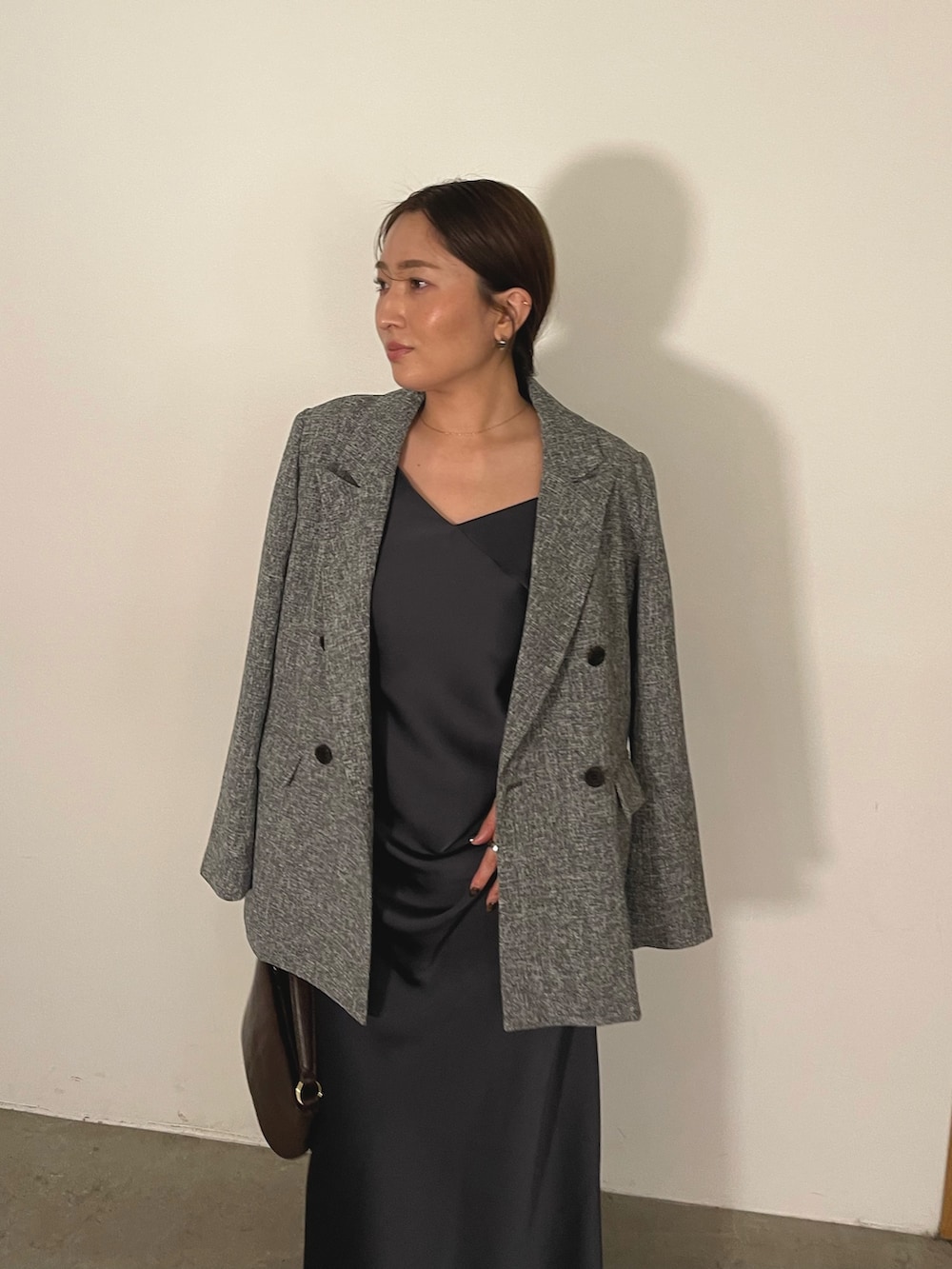 グレー系のドレス、ブラウン系のハンドバッグ、ゴールド系のパンプスを着用したレディースの冬コーディネートの8枚目の写真