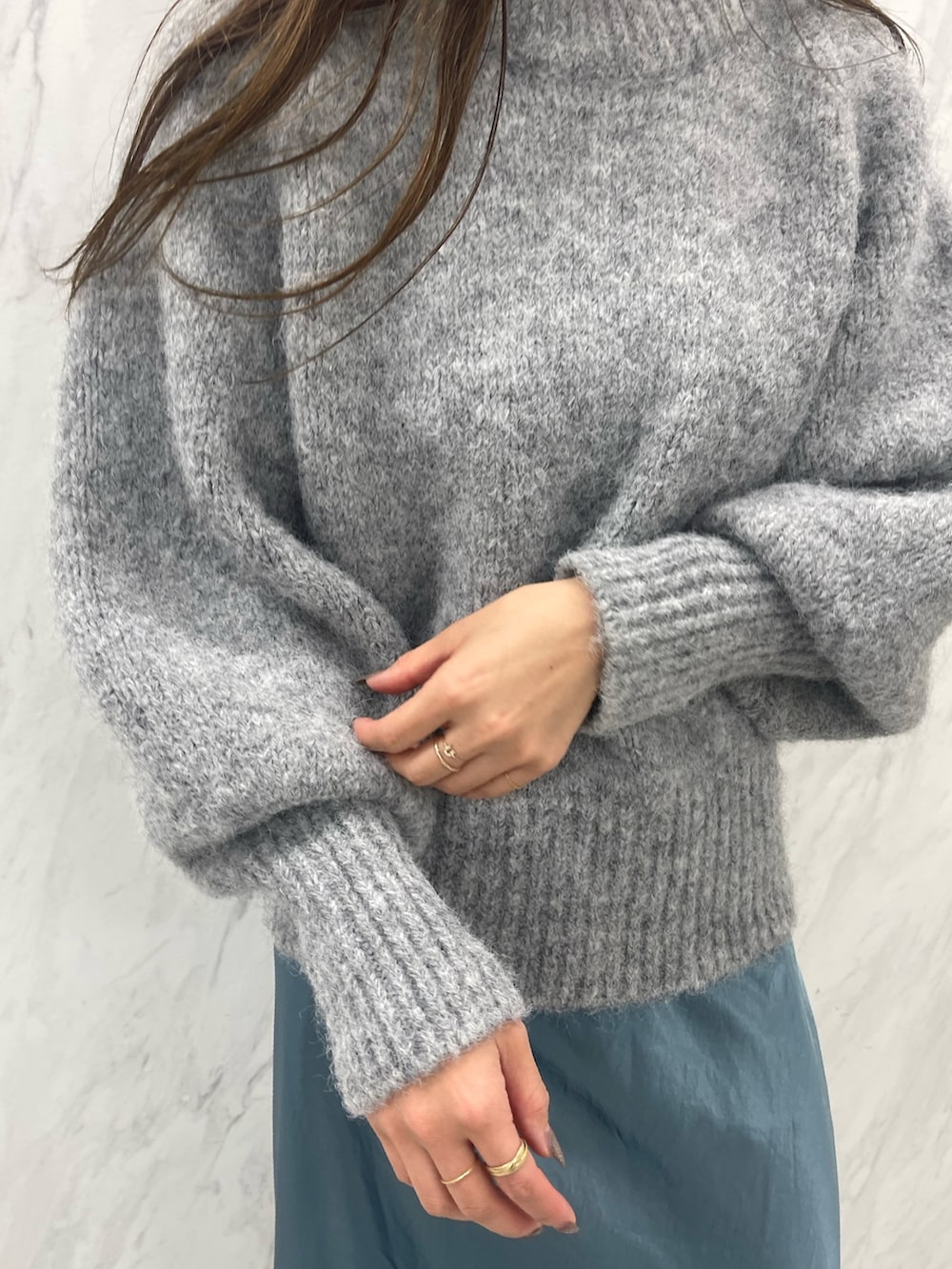 グレー系のニット/セーター、ブルー系のスカート、ブラック系のスニーカーを着用したレディースの冬コーディネートの9枚目の写真