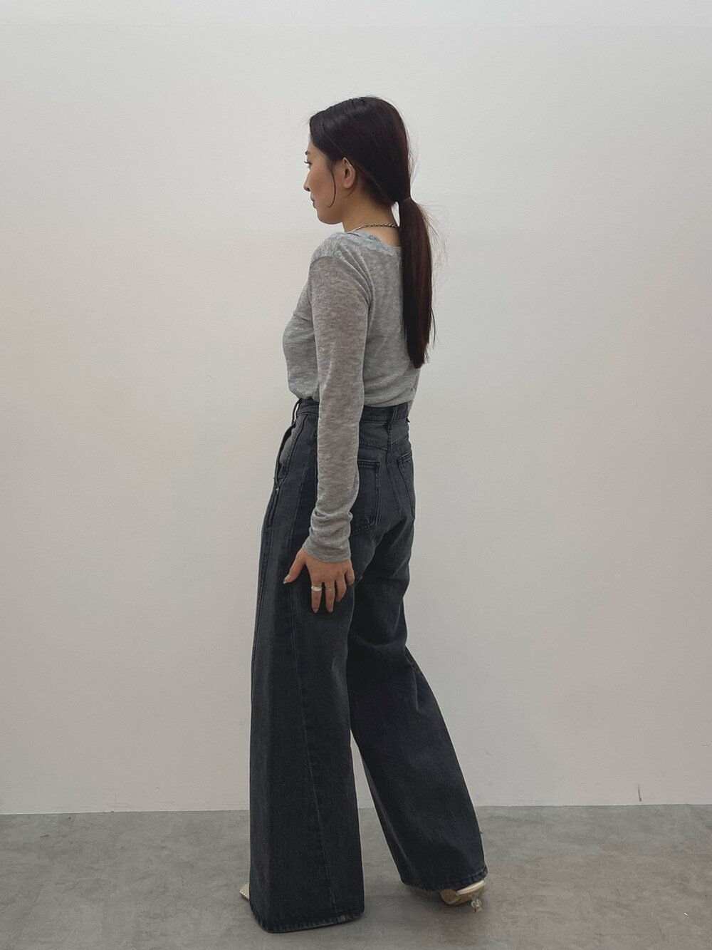 ブラック系のデニムパンツ、ホワイト系のサンダル、グレー系のTシャツ/カットソーを着用したレディースの春コーディネートの3枚目の写真