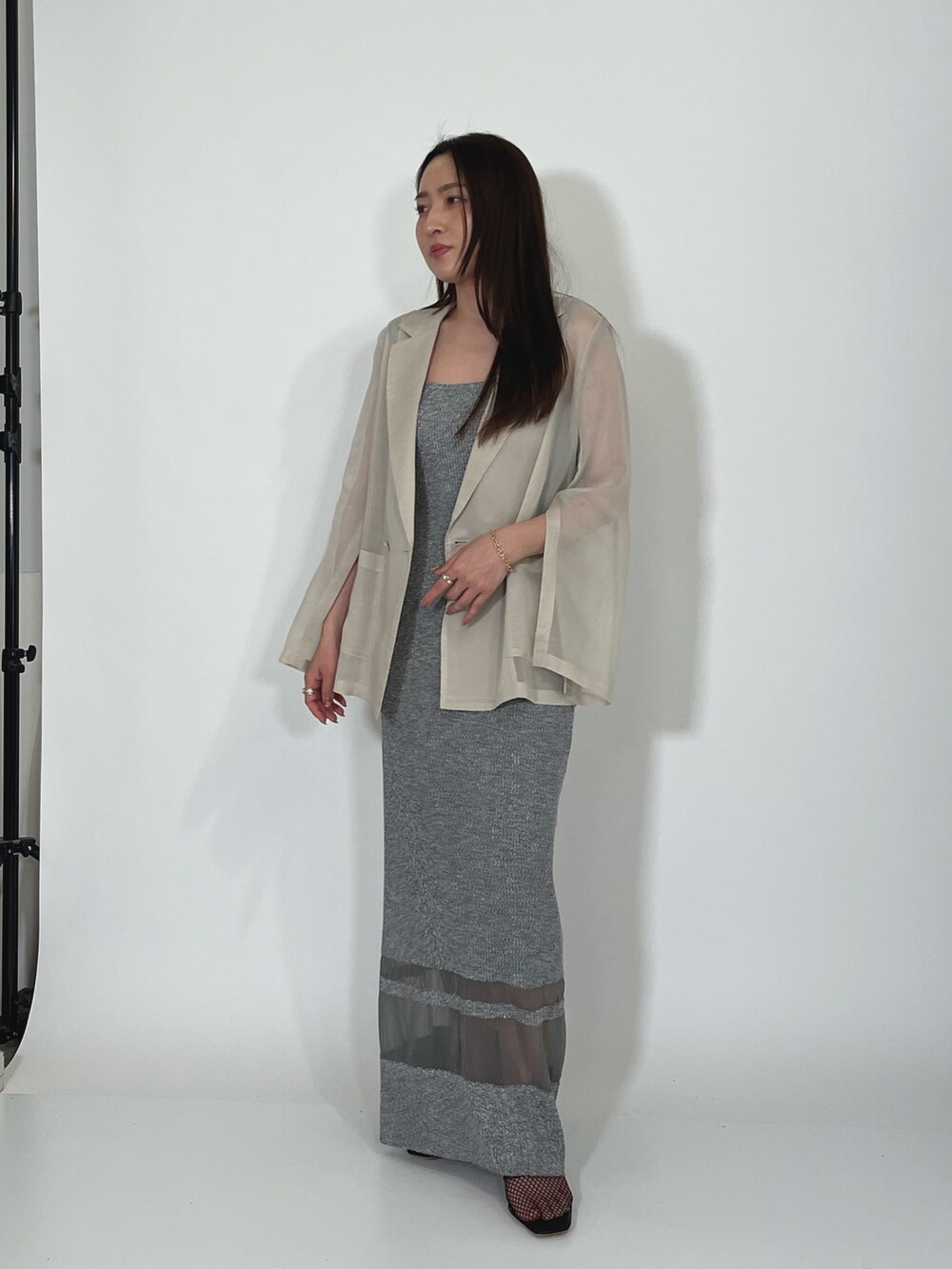 ホワイト系のテーラードジャケット、グレー系のワンピース、ブラック系のサンダルを着用したレディースの夏コーディネートの3枚目の写真