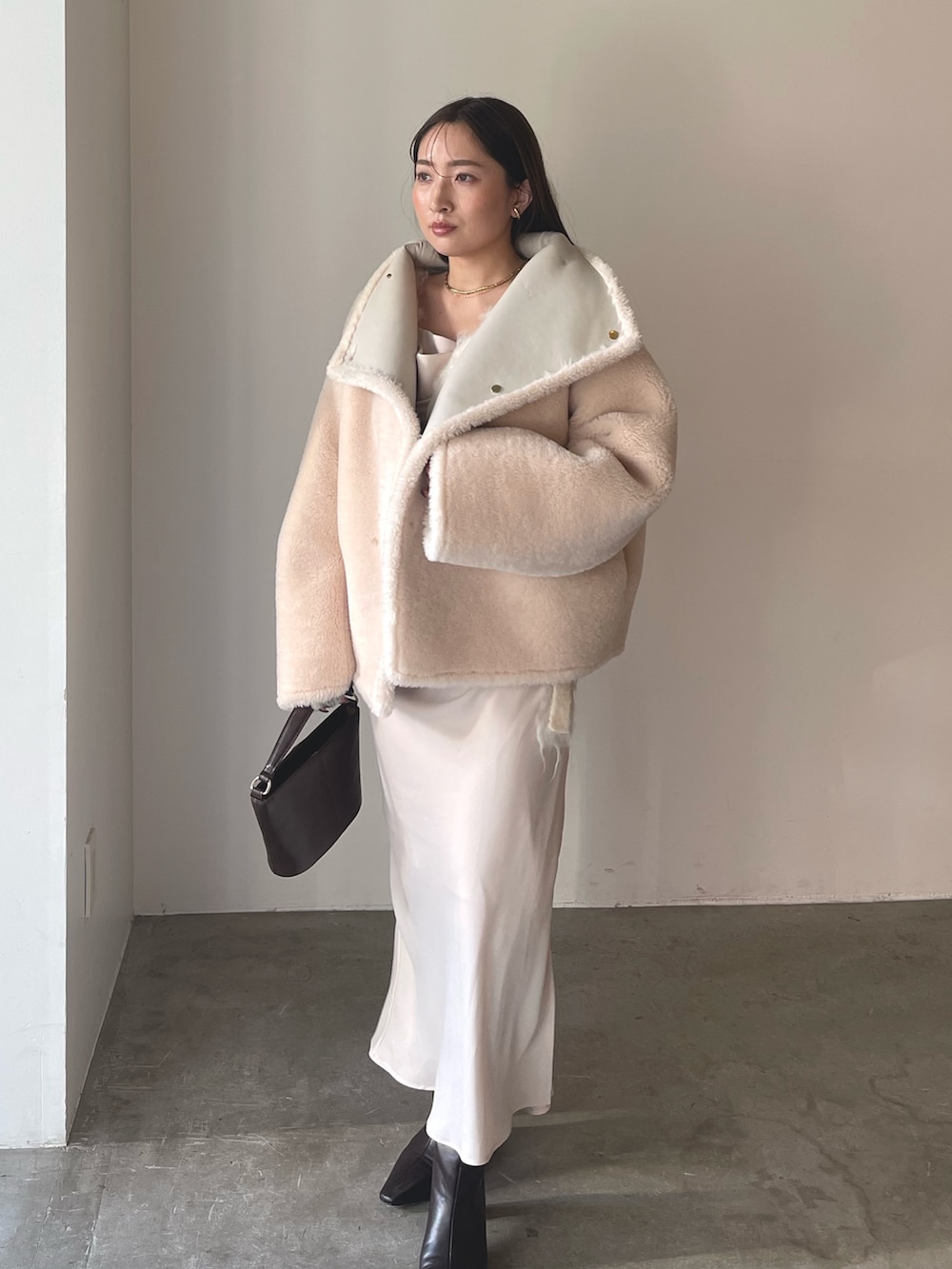 ベージュ系のワンピース、ブラウン系のハンドバッグ、ブラウン系のブーツを着用したレディースの冬コーディネートの7枚目の写真