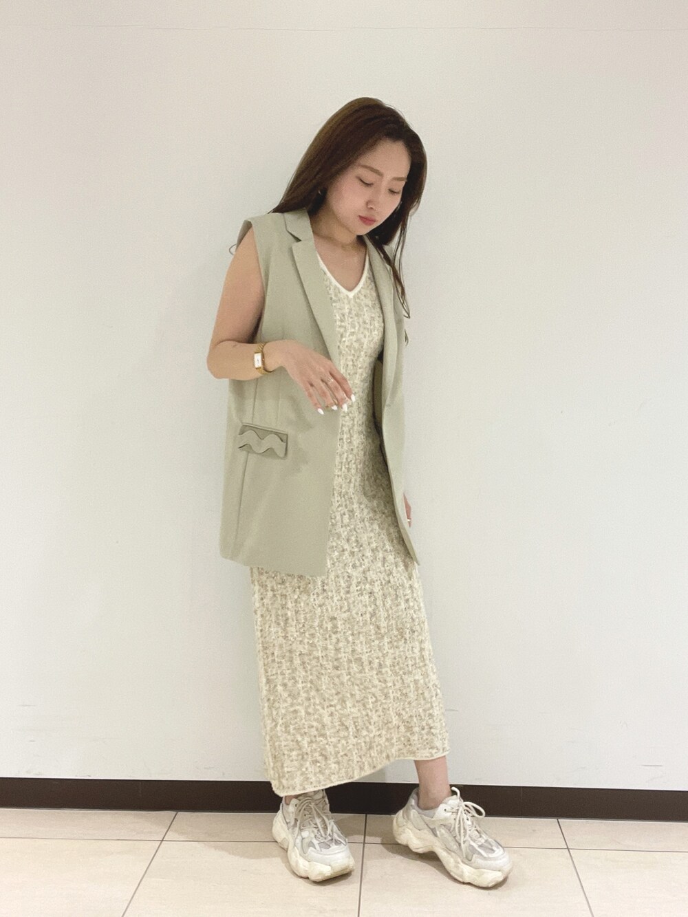 ホワイト系のワンピース、ベージュ系のベストを着用したレディースの春コーディネートの3枚目の写真