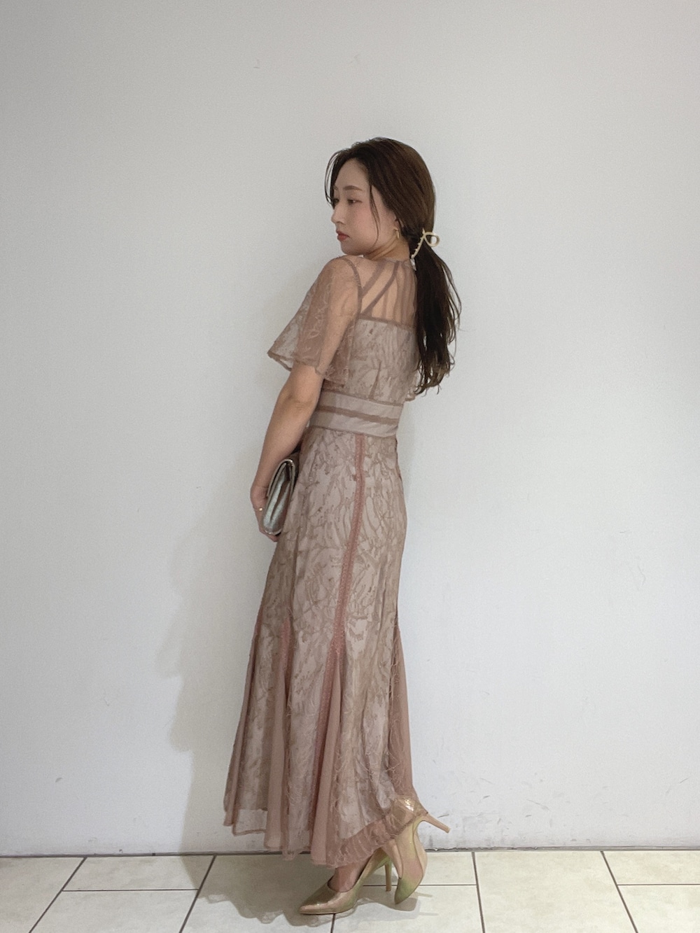 ブラウン系のドレス、ゴールド系のパンプス、ゴールド系のハンドバッグを着用したレディースの冬コーディネートの5枚目の写真