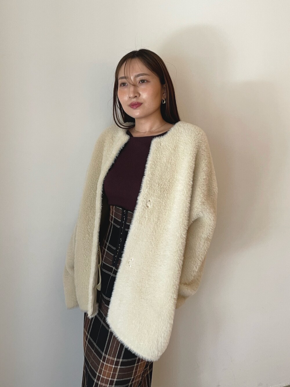 ブラウン系のニット/セーター、ブラウン系のスカート、ブラック系のブーツを着用したレディースの秋コーディネートの7枚目の写真