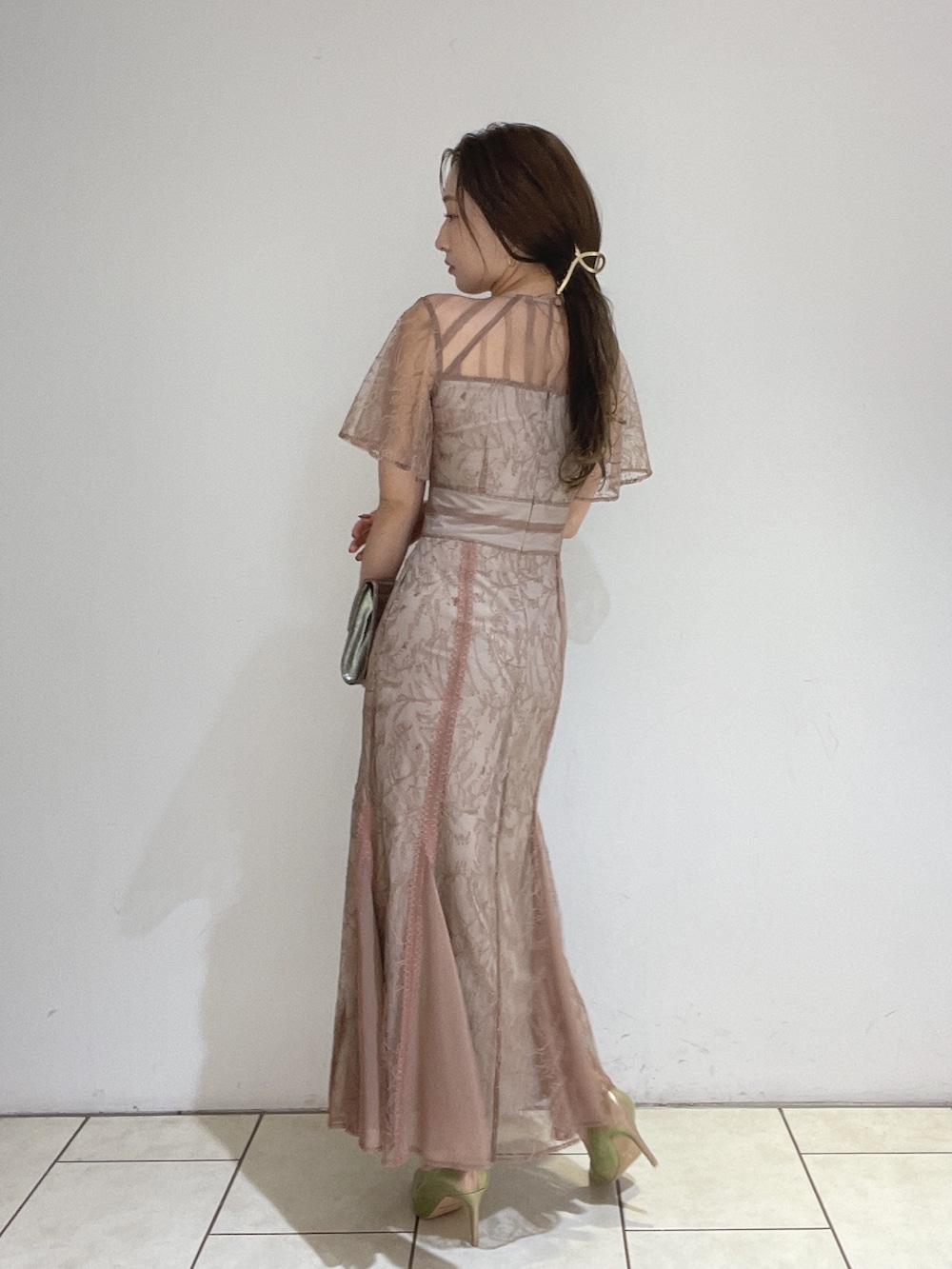 ブラウン系のドレス、ゴールド系のパンプス、ゴールド系のハンドバッグを着用したレディースの冬コーディネートの6枚目の写真