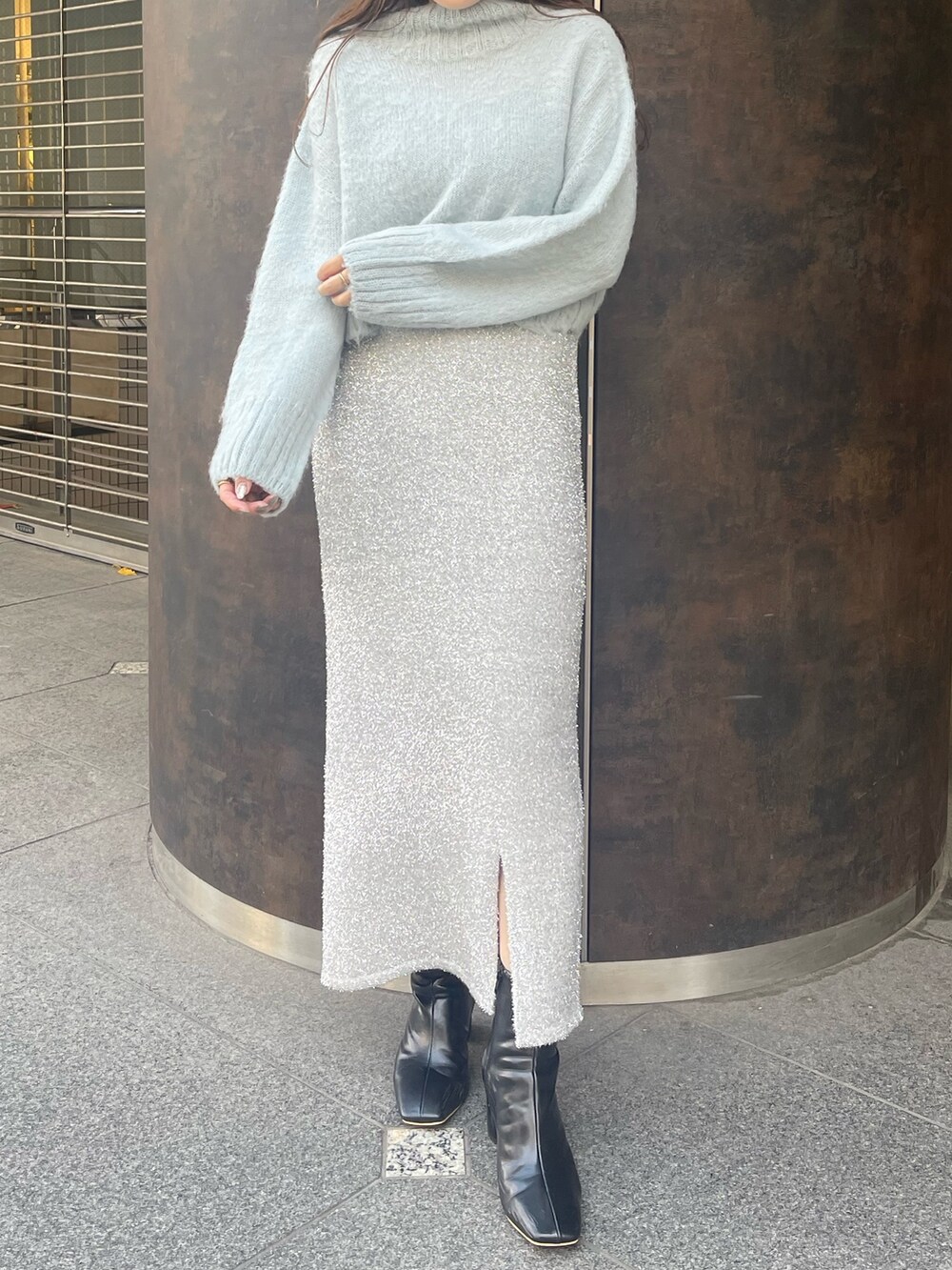 シルバー系のスカート、ブラック系のブーツ、グリーン系のニット/セーターを着用したレディースの冬コーディネートの4枚目の写真