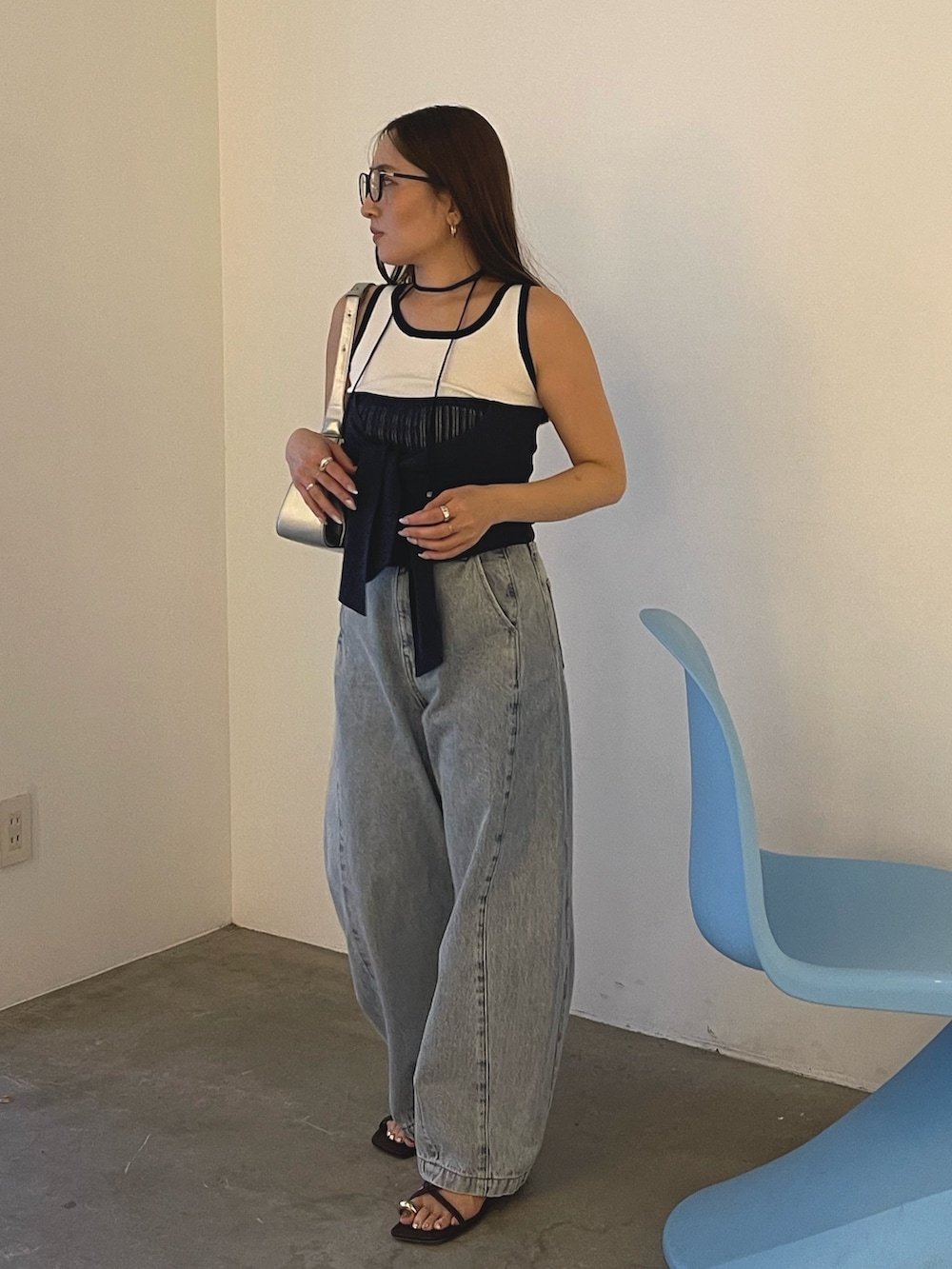 ブルー系のデニムパンツ、シルバー系のハンドバッグ、ブラウン系のサンダルを着用したレディースの春コーディネートの4枚目の写真