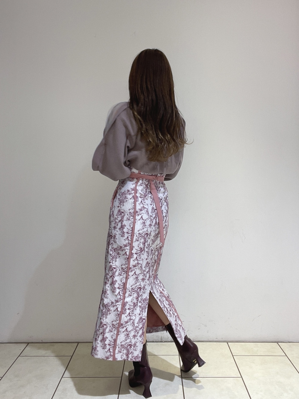 ピンク系のスカート、ブラウン系のニット/セーター、レッド系のブーツを着用したレディースの冬コーディネートの6枚目の写真