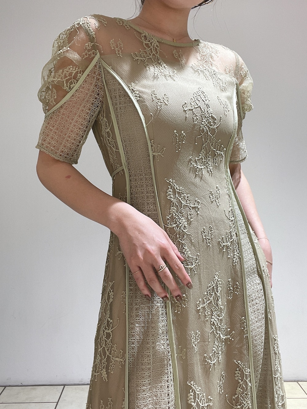 ゴールド系のハンドバッグ、グリーン系のドレス、ゴールド系のパンプスを着用したレディースの冬コーディネートの8枚目の写真