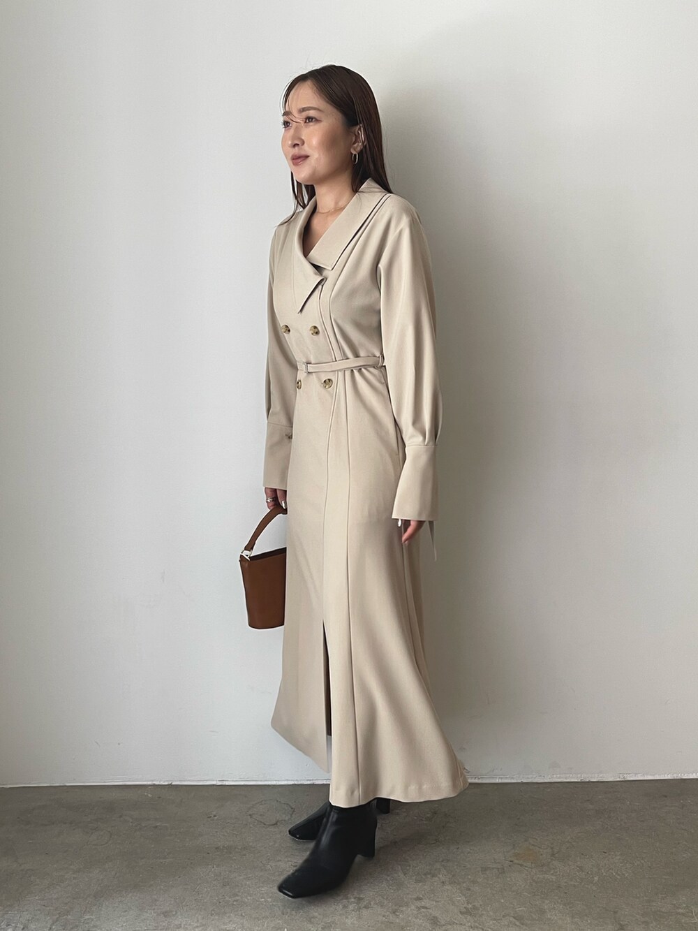 ブラック系のブーツ、ベージュ系のワンピース、イエロー系のハンドバッグを着用したレディースの秋コーディネートの5枚目の写真