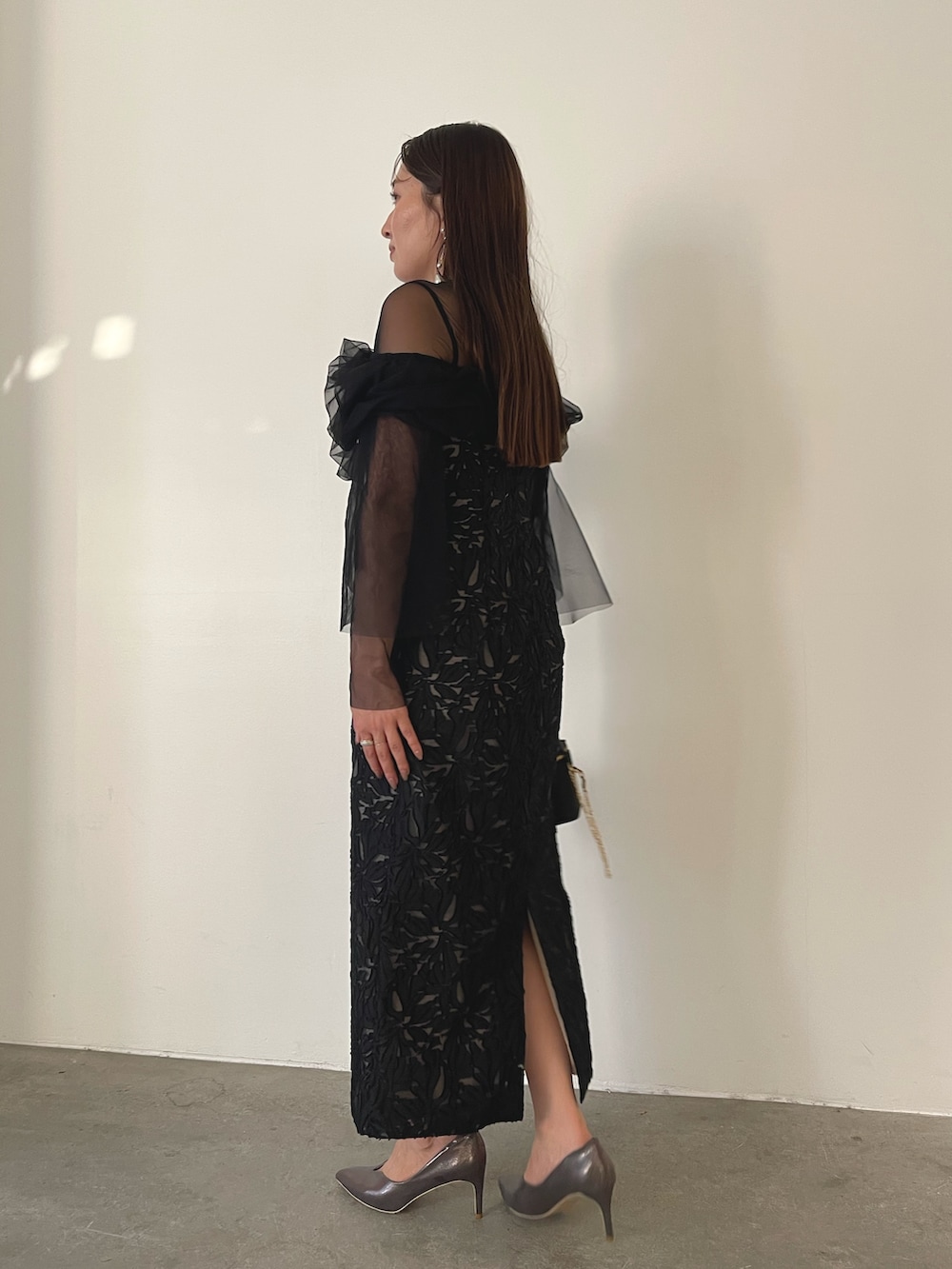 シルバー系のパンプス、ブラック系のハンドバッグ、ブラック系のドレスを着用したレディースの秋コーディネートの5枚目の写真