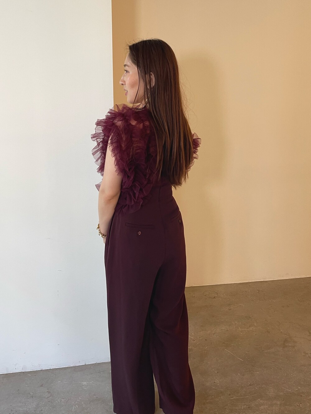 ゴールド系のクラッチバッグ、レッド系のパンツドレス、ゴールド系のピアス(両耳用)を着用したレディースの夏コーディネートの5枚目の写真