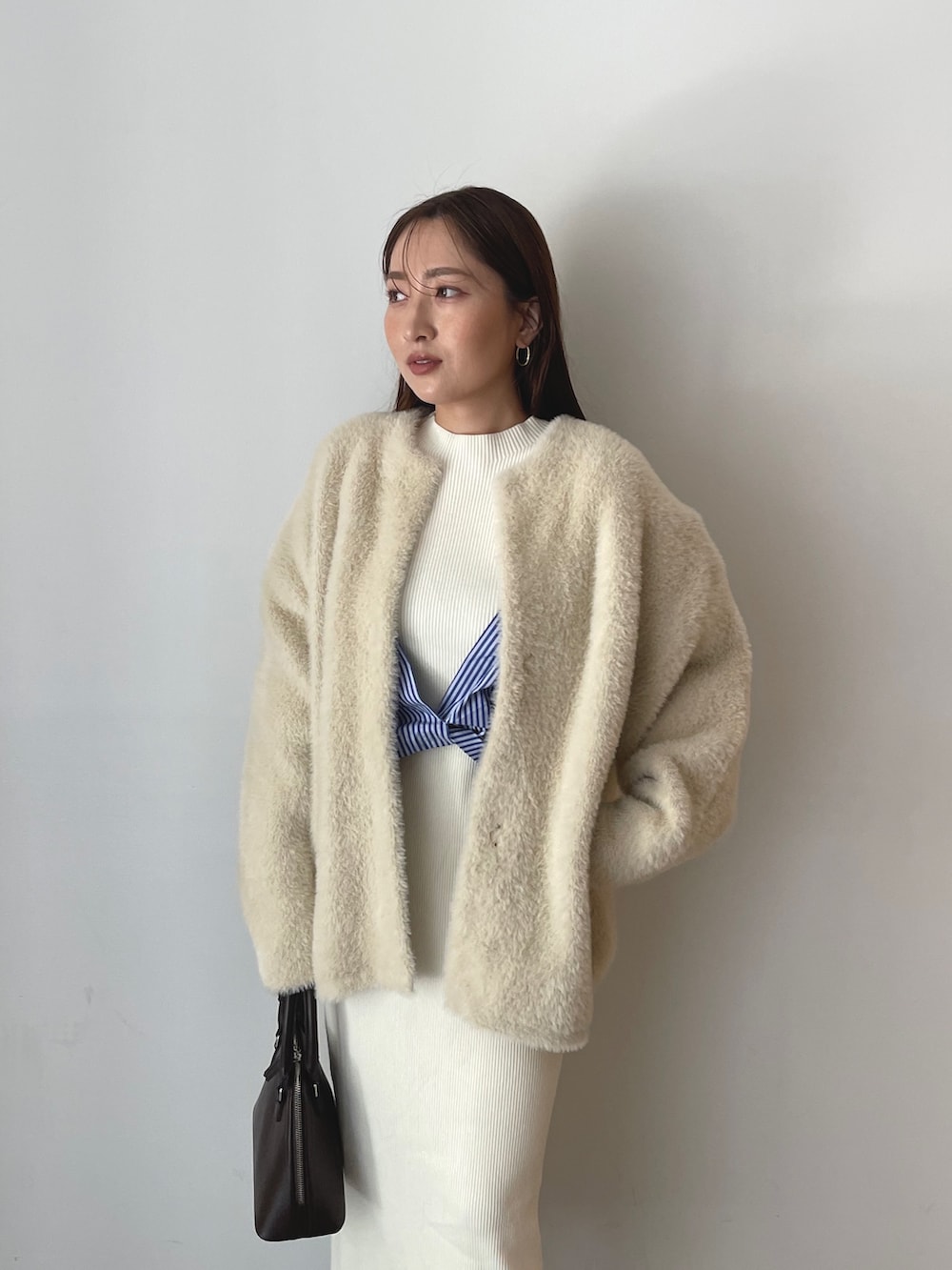 ブラウン系のボストンバッグ、ブラック系のブーツ、ホワイト系のワンピースを着用したレディースの秋コーディネートの8枚目の写真