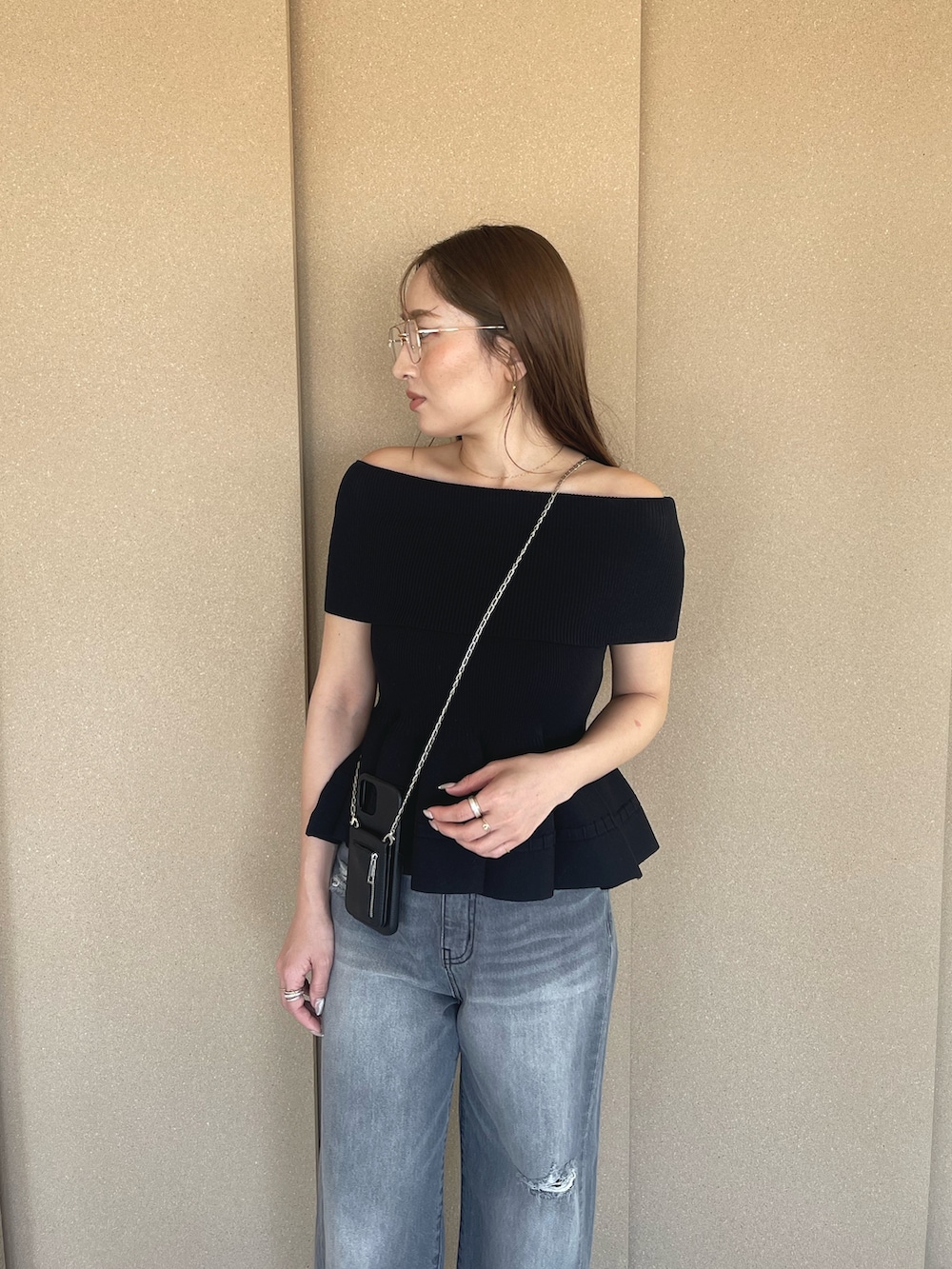 ブラック系のニット/セーター、グレー系のデニムパンツ、オレンジ系のサンダルを着用したレディースの春コーディネートの7枚目の写真