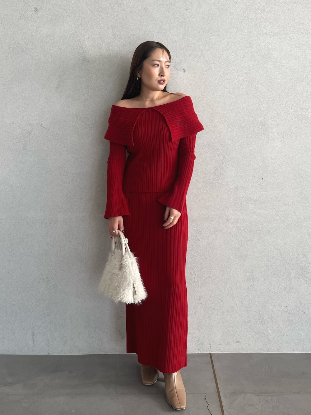 レッド系のニット/セーター、ベージュ系のブーツ、レッド系のスカートを着用したレディースの秋コーディネートの2枚目の写真