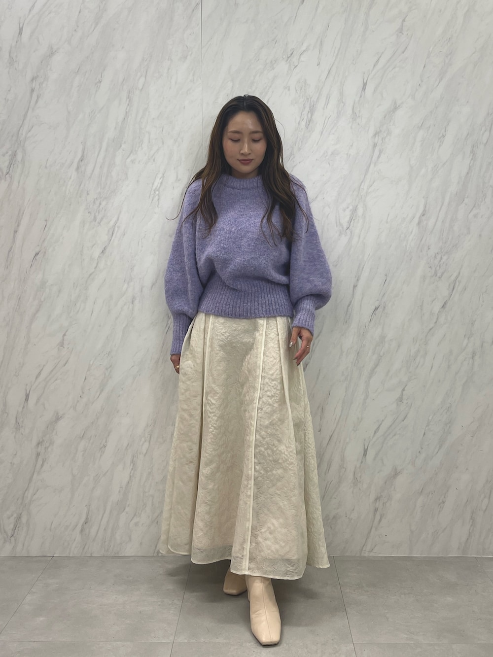 ホワイト系のスカート、ホワイト系のブーツ、パープル系のニット/セーターを着用したレディースの冬コーディネートの2枚目の写真