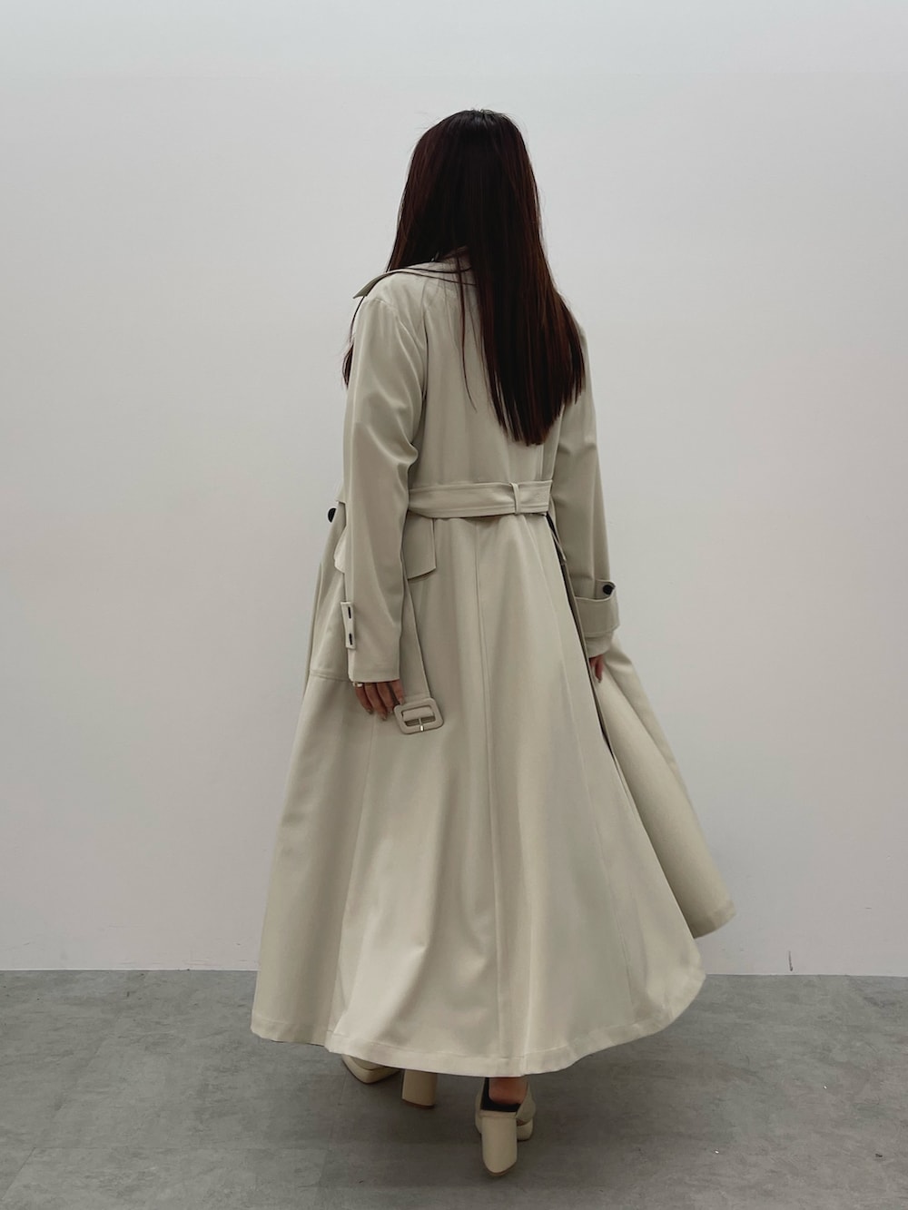 ホワイト系のトレンチコート、ブラック系のワンピース、ホワイト系のサンダルを着用したレディースの春コーディネートの6枚目の写真