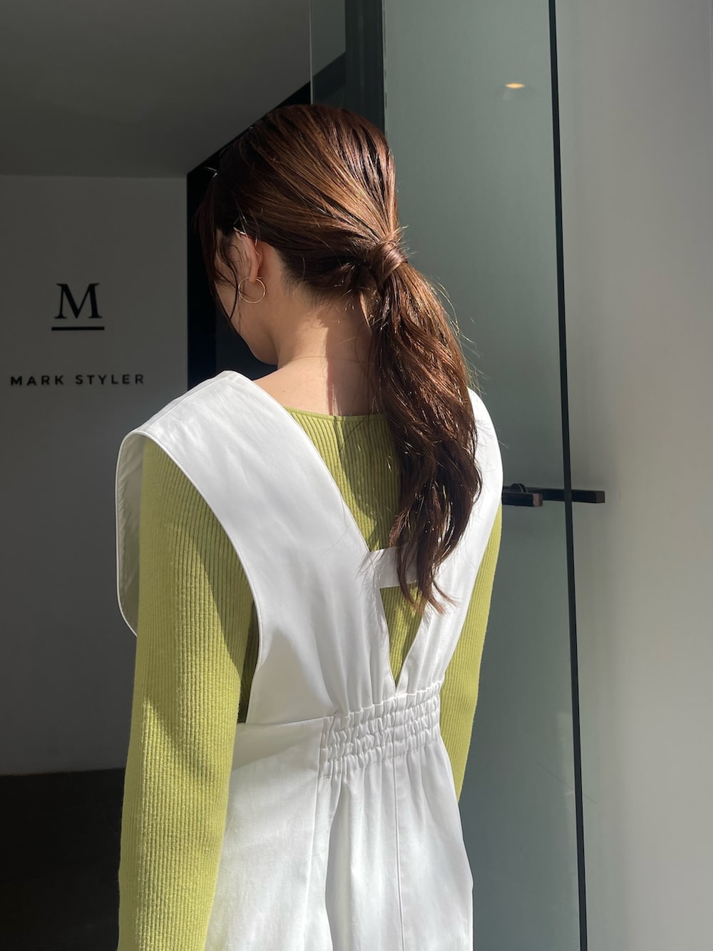 シルバー系のパンプス、グリーン系のニット/セーター、ホワイト系のジャンパースカートを着用したレディースの冬コーディネートの7枚目の写真