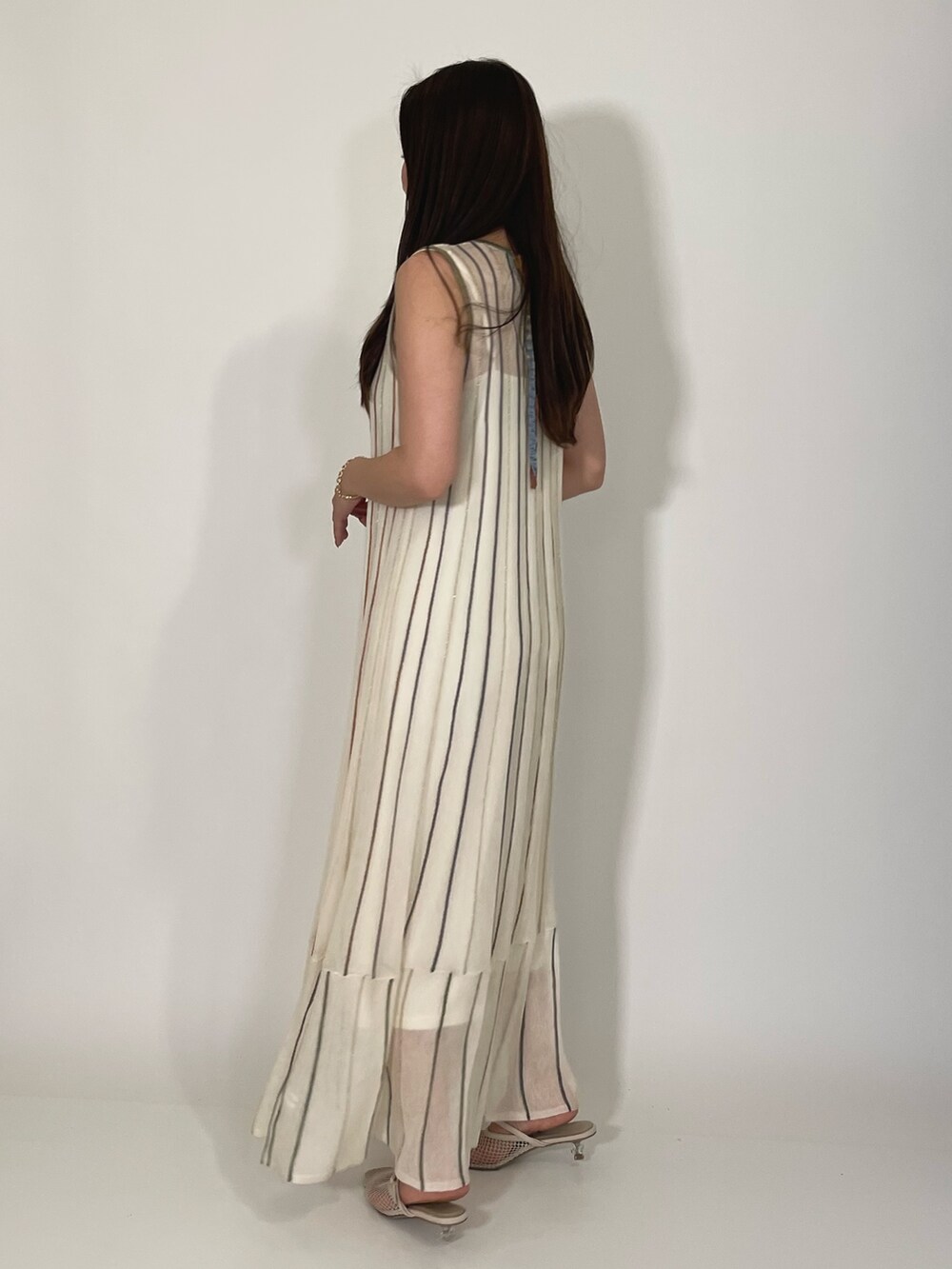 ホワイト系のサンダル、ホワイト系のワンピース、ゴールド系のブレスレットを着用したレディースの夏コーディネートの5枚目の写真