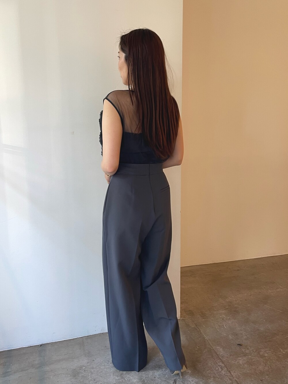 シルバー系のパンプス、グレー系のパンツドレス、ゴールド系のピアス（両耳用）を着用したレディースの夏コーディネートの3枚目の写真