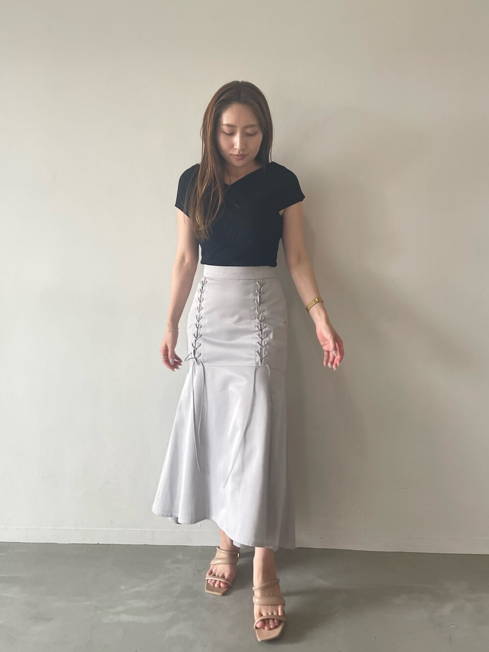 ブラック系のニット/セーター、グレー系のスカート、ベージュ系のサンダルを着用したレディースの夏コーディネートの2枚目の写真