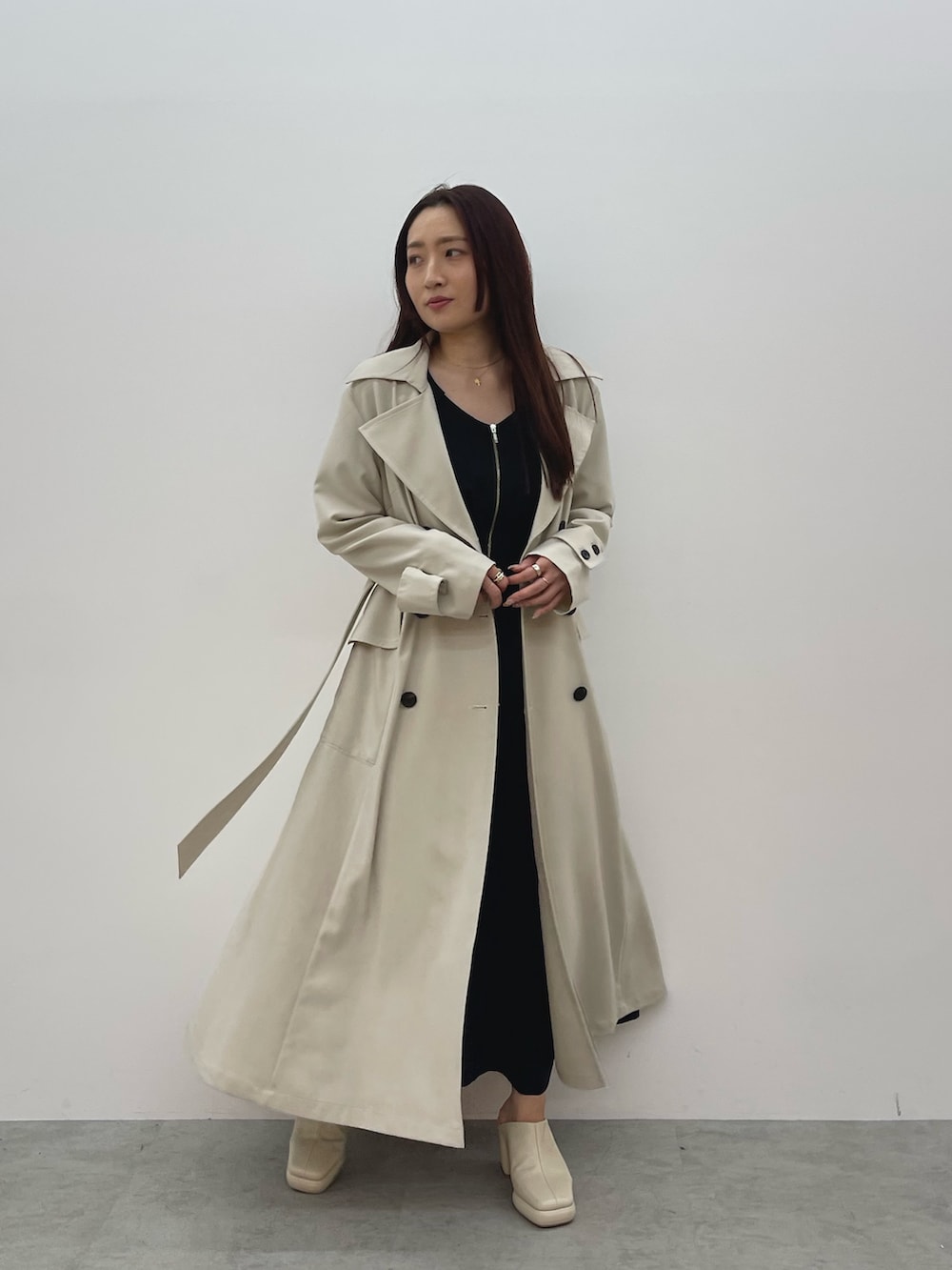 ホワイト系のトレンチコート、ブラック系のワンピース、ホワイト系のサンダルを着用したレディースの春コーディネートの2枚目の写真