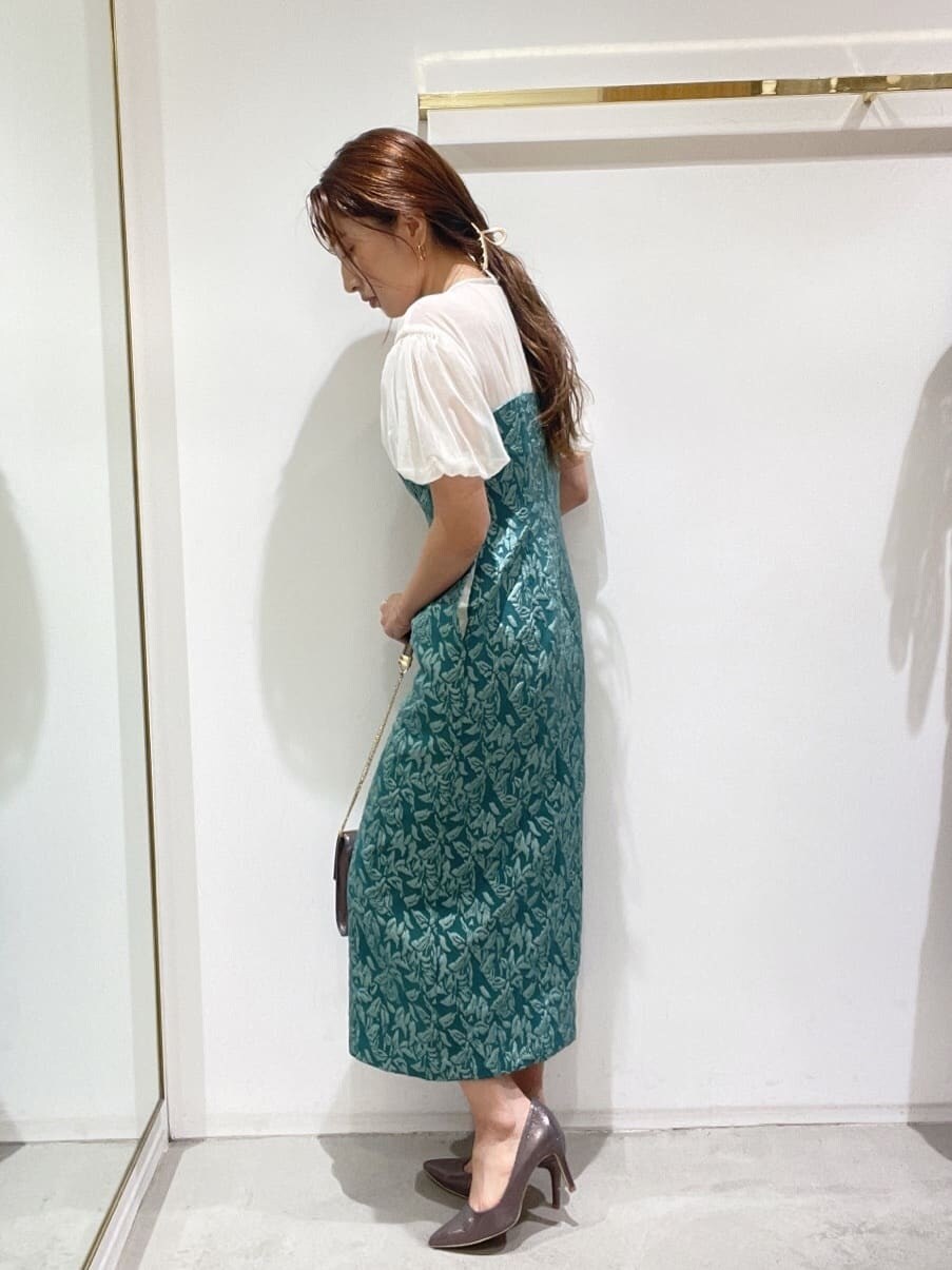 シルバー系のクラッチバッグ、シルバー系のパンプス、グリーン系のドレスを着用したレディースの秋コーディネートの7枚目の写真