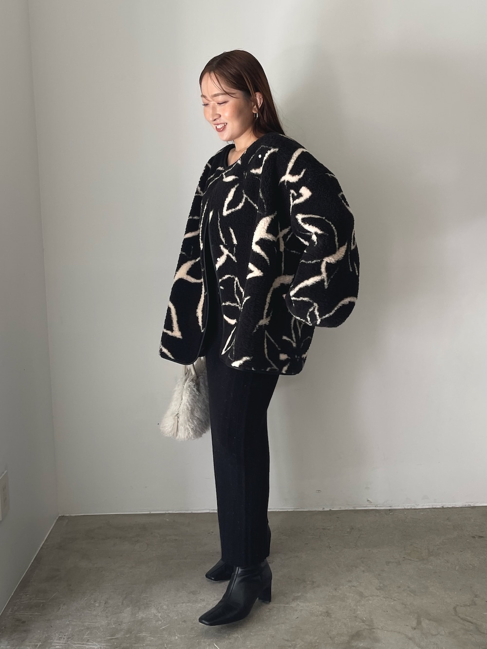 ブラック系のブーツ、ホワイト系のボストンバッグ、ブラック系のブルゾンを着用したレディースの秋コーディネートの3枚目の写真