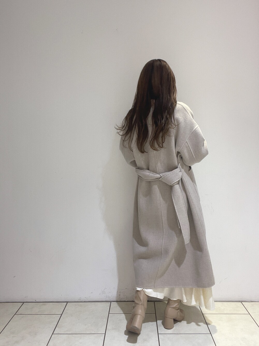 ホワイト系のスカート、ベージュ系のその他アウター、グリーン系のニット/セーターを着用したレディースの冬コーディネートの6枚目の写真