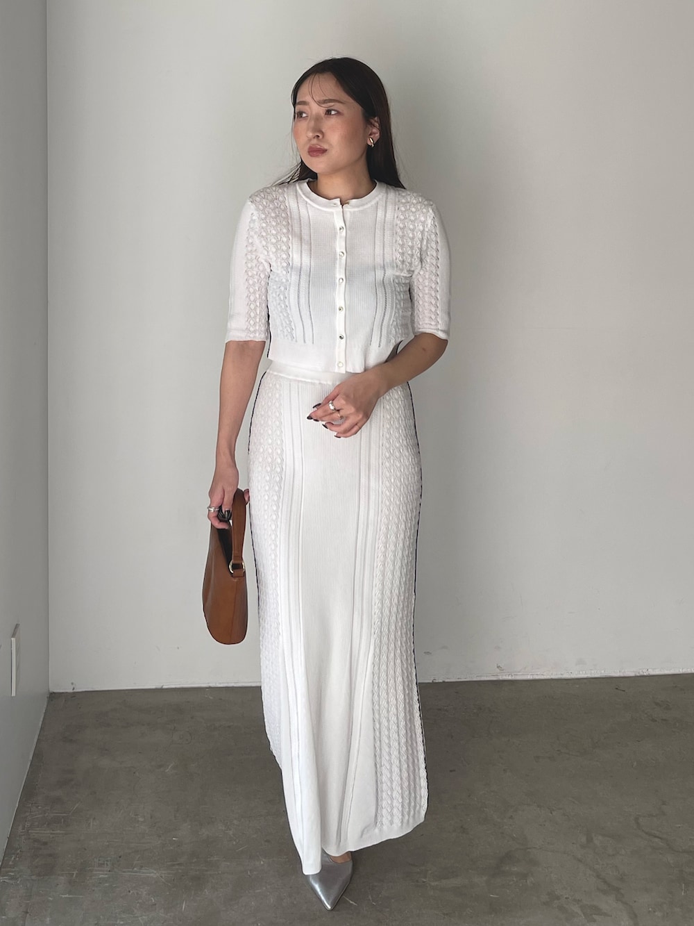 イエロー系のハンドバッグ、シルバー系のパンプス、ホワイト系のワンピースを着用したレディースの冬コーディネートの3枚目の写真