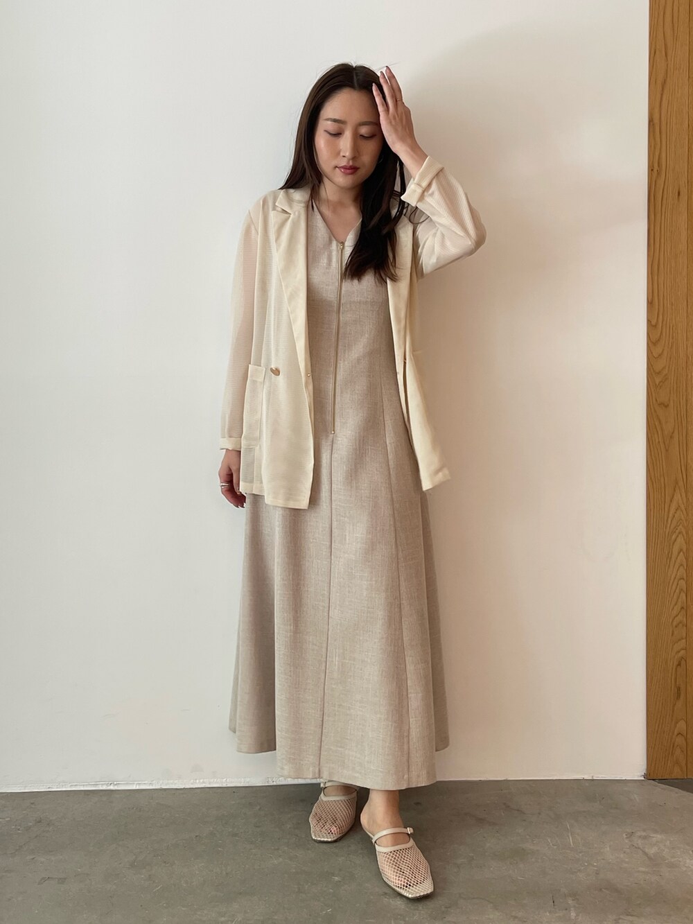 ベージュ系のワンピース、ホワイト系のサンダル、ホワイト系のテーラードジャケットを着用したレディースの夏コーディネートの2枚目の写真