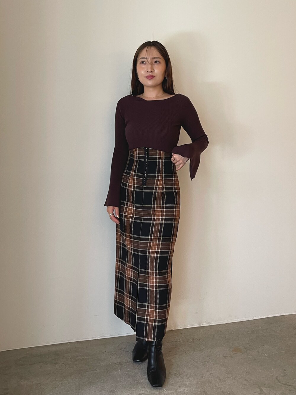 ブラウン系のニット/セーター、ブラウン系のスカート、ブラック系のブーツを着用したレディースの秋コーディネートの8枚目の写真
