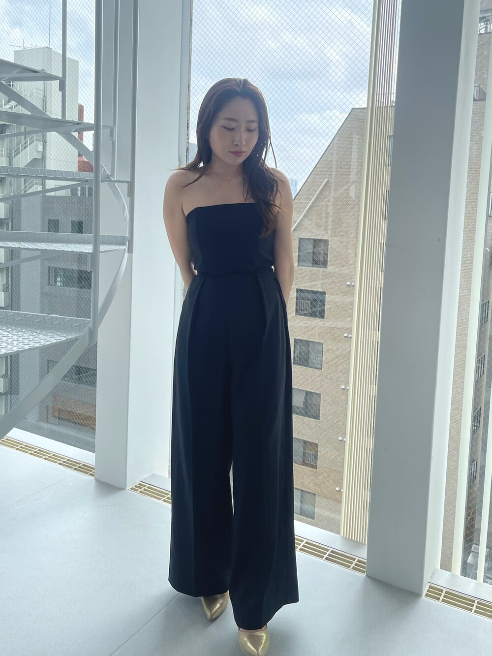 ゴールド系のパンプス、ブラック系のパンツドレスを着用したレディースの夏コーディネートの8枚目の写真