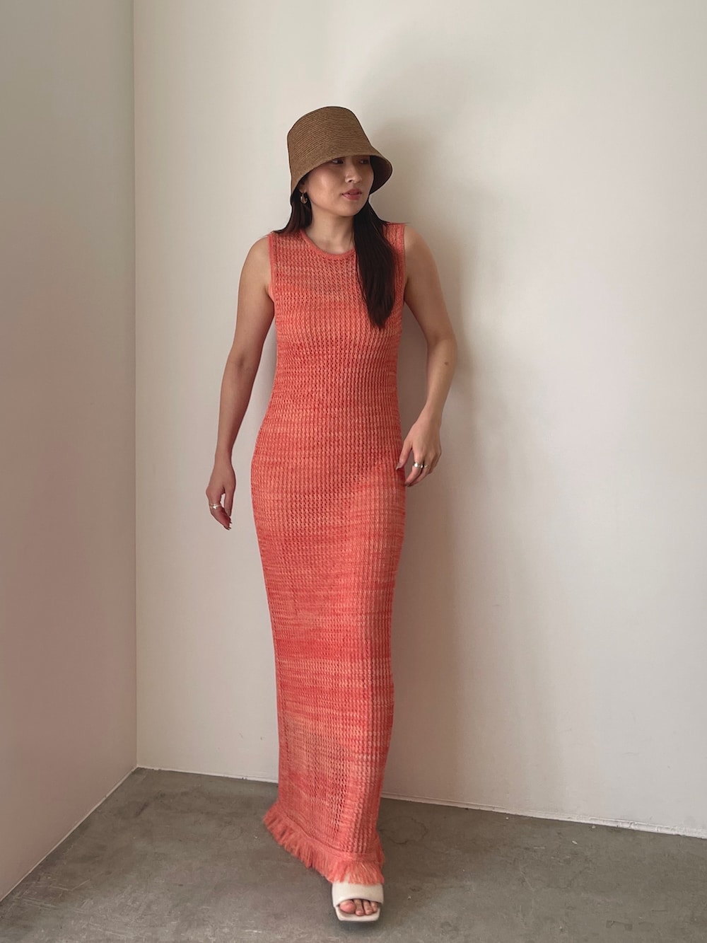 ホワイト系のサンダル、オレンジ系のワンピース、ブラウン系のハットを着用したレディースの春コーディネートの3枚目の写真