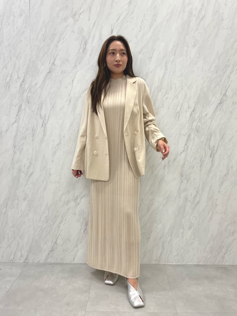 シルバー系のパンプス、ベージュ系のテーラードジャケット、ホワイト系のワンピースを着用したレディースの春コーディネートの3枚目の写真