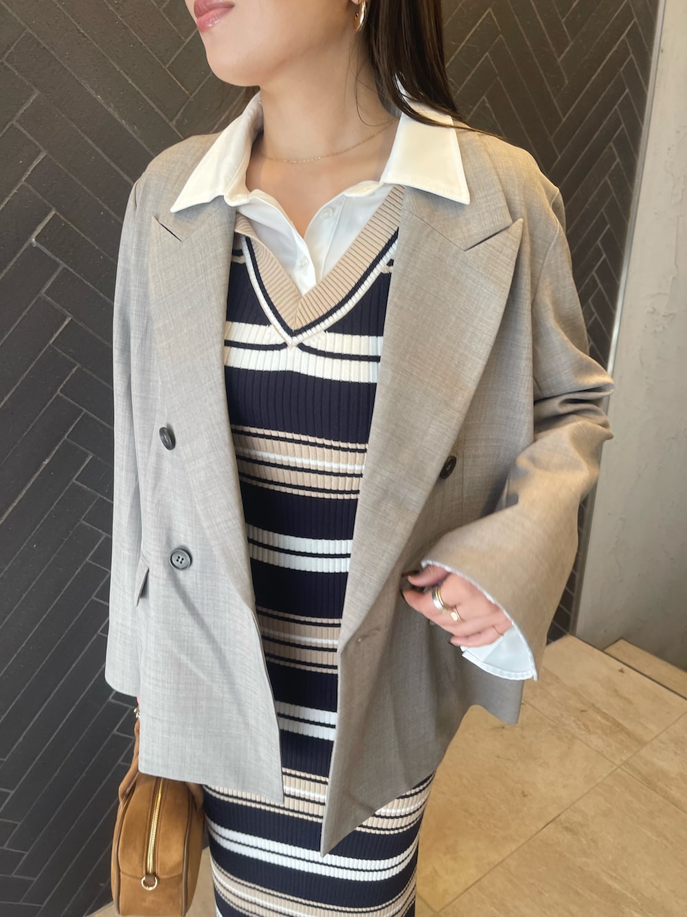 イエロー系のハンドバッグ、ベージュ系のワンピース、グレー系のテーラードジャケットを着用したレディースの冬コーディネートの9枚目の写真