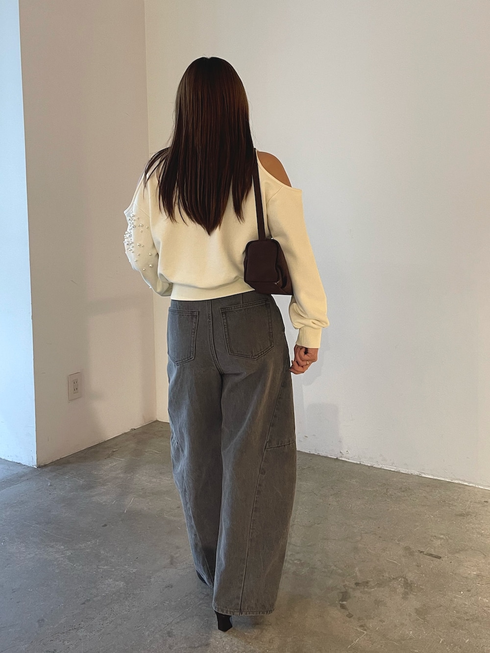 グレー系のデニムパンツ、ブラック系のブーツ、ブラウン系のハンドバッグを着用したレディースの秋コーディネートの6枚目の写真