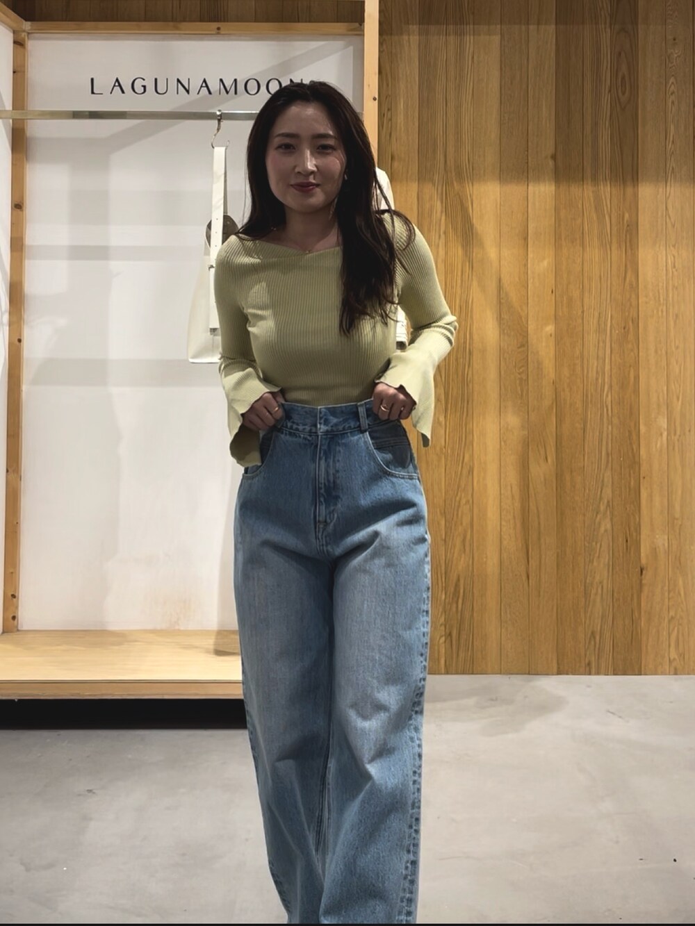 グリーン系のニット/セーター、ホワイト系のパンプス、ブルー系のデニムパンツを着用したレディースの冬コーディネートの5枚目の写真