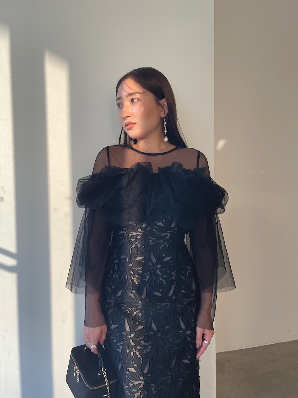 シルバー系のパンプス、ブラック系のハンドバッグ、ブラック系のドレスを着用したレディースの秋コーディネートの9枚目の写真