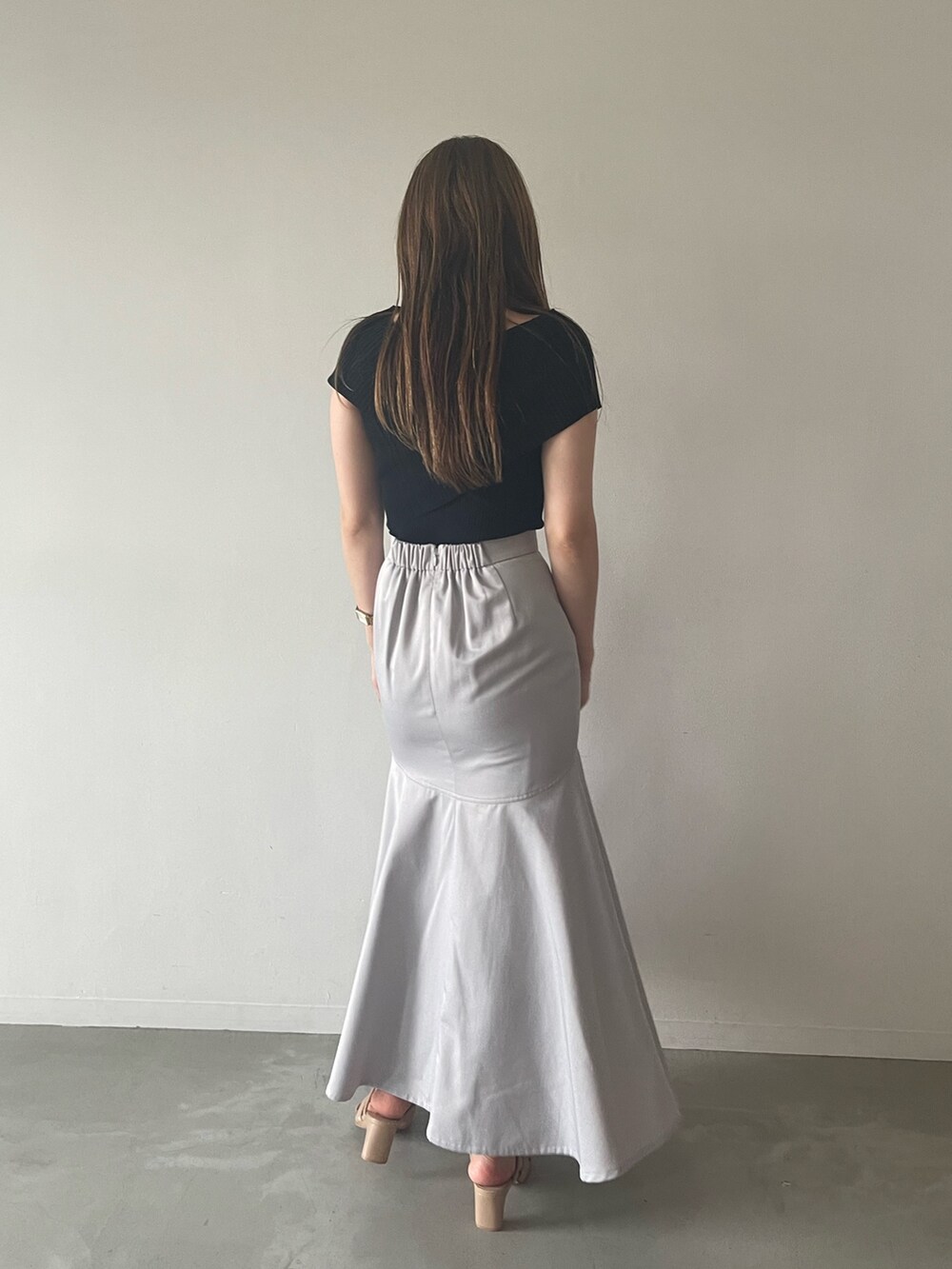 ブラック系のニット/セーター、グレー系のスカート、ベージュ系のサンダルを着用したレディースの夏コーディネートの3枚目の写真