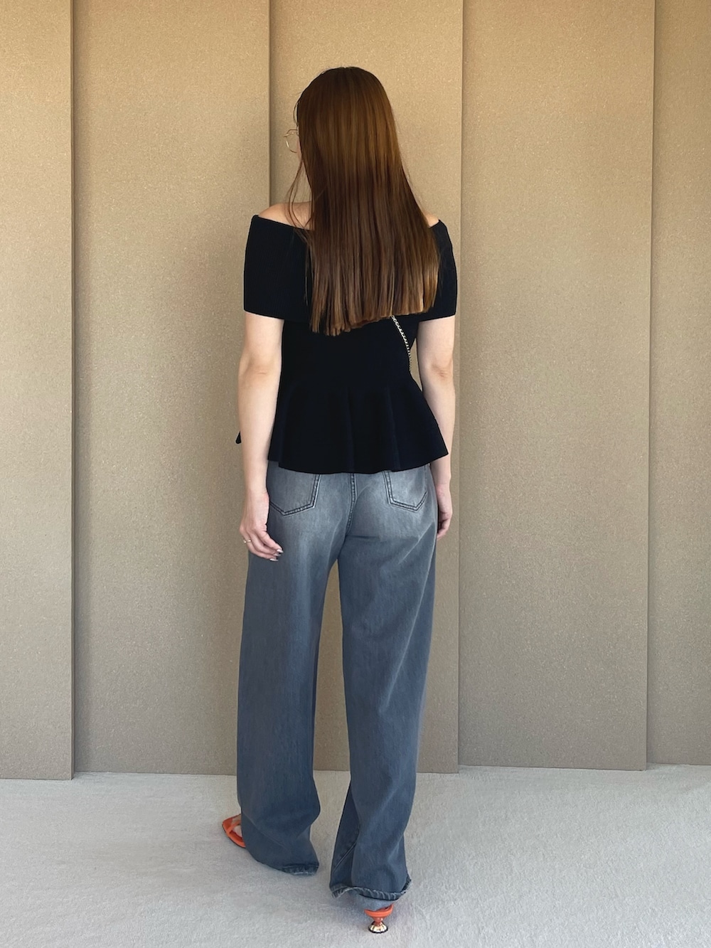 ブラック系のニット/セーター、グレー系のデニムパンツ、オレンジ系のサンダルを着用したレディースの春コーディネートの4枚目の写真