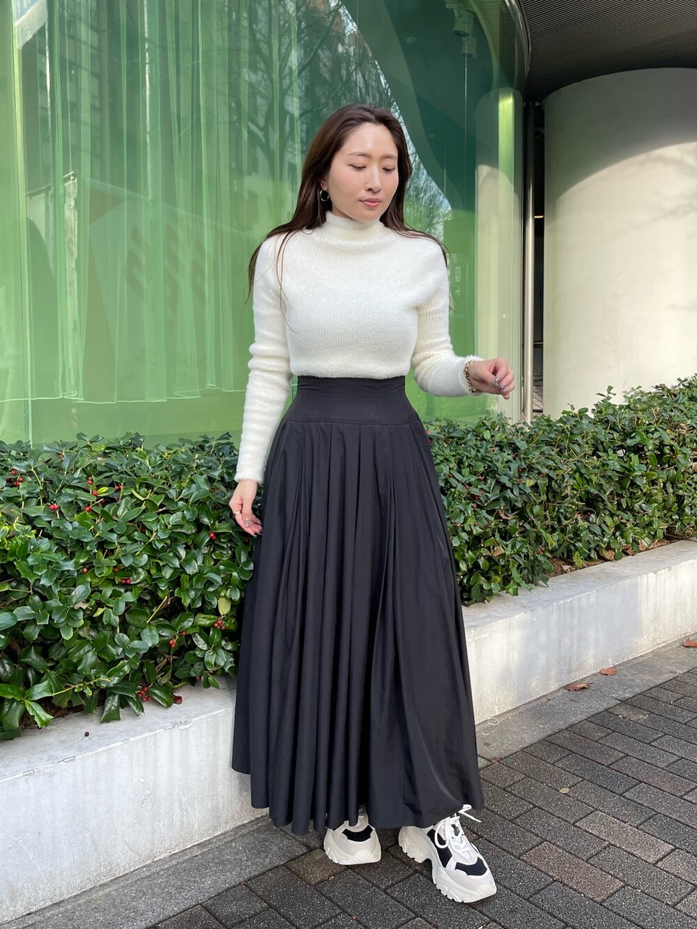 ブラック系のスニーカー、ホワイト系のニット/セーター、ブラック系のスカートを着用したレディースの冬コーディネートの3枚目の写真