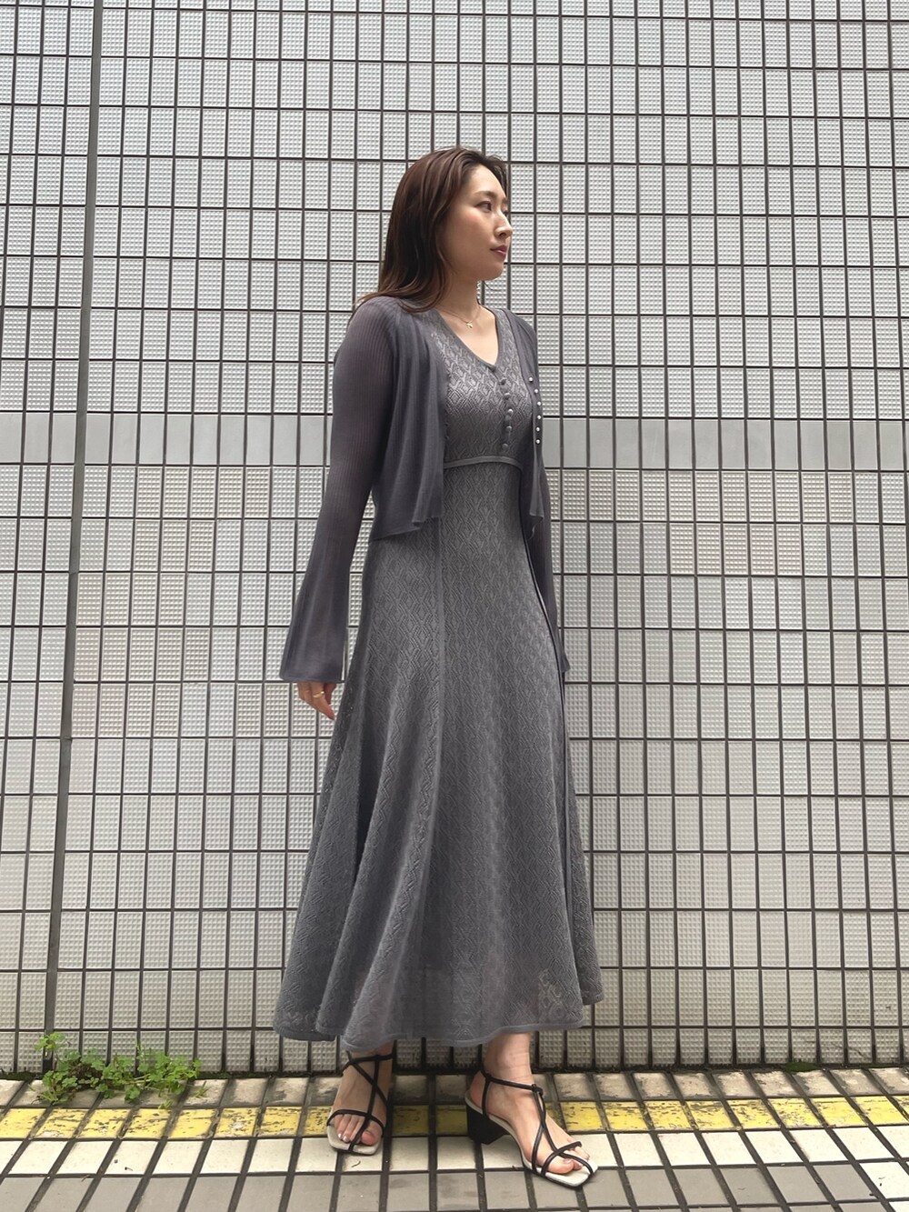 グレー系のワンピース、ブラック系のサンダル、グレー系のカーディガン/ボレロを着用したレディースの春コーディネートの2枚目の写真