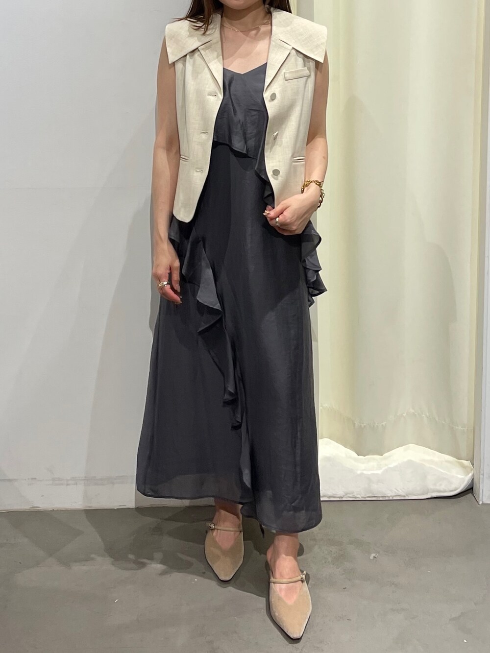 ホワイト系のベスト、グレー系のワンピース、ベージュ系のパンプスを着用したレディースの夏コーディネートの2枚目の写真