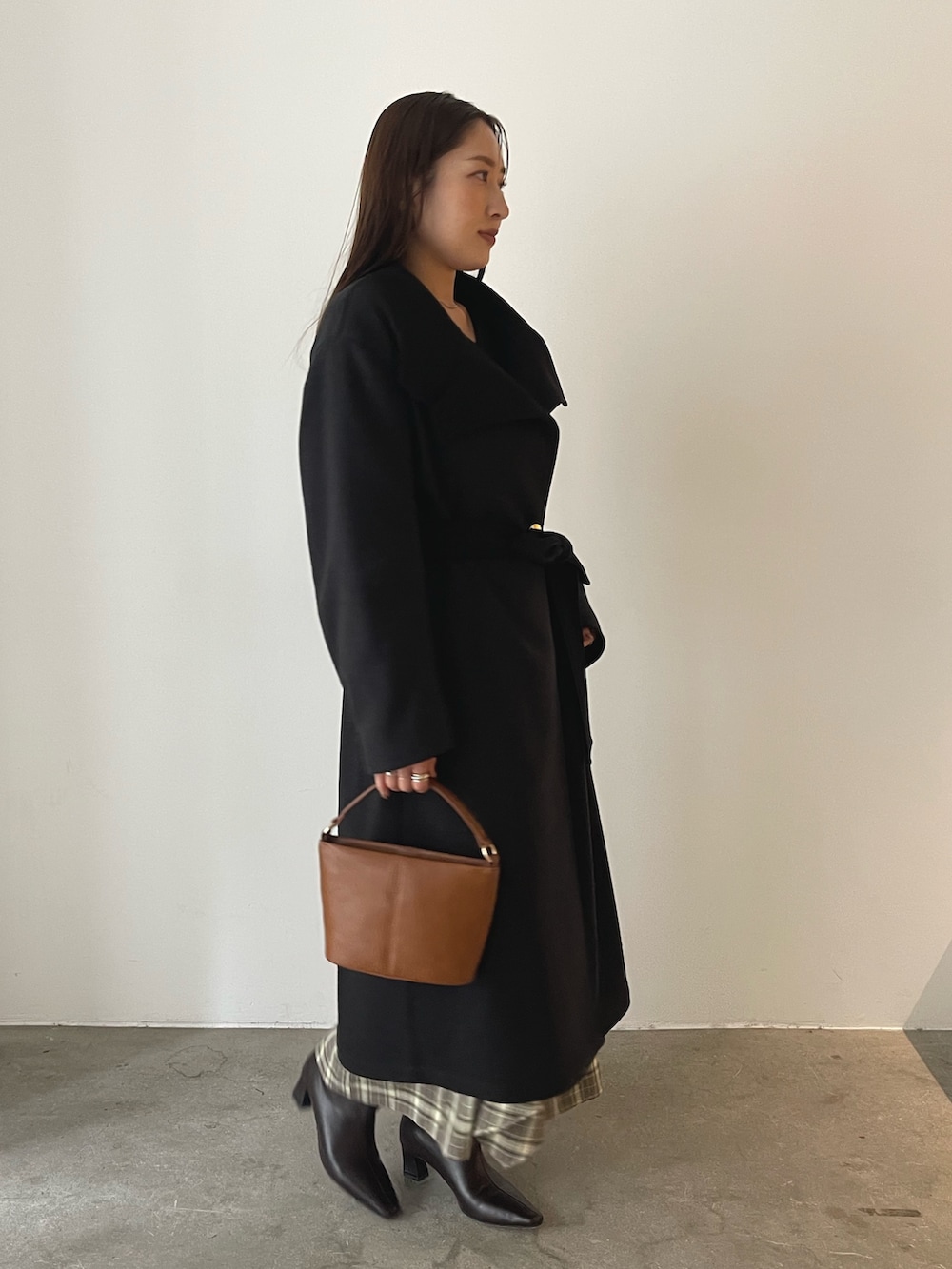 ブラウン系のスカート、イエロー系のハンドバッグ、グレー系のチェスターコートを着用したレディースの秋コーディネートの3枚目の写真