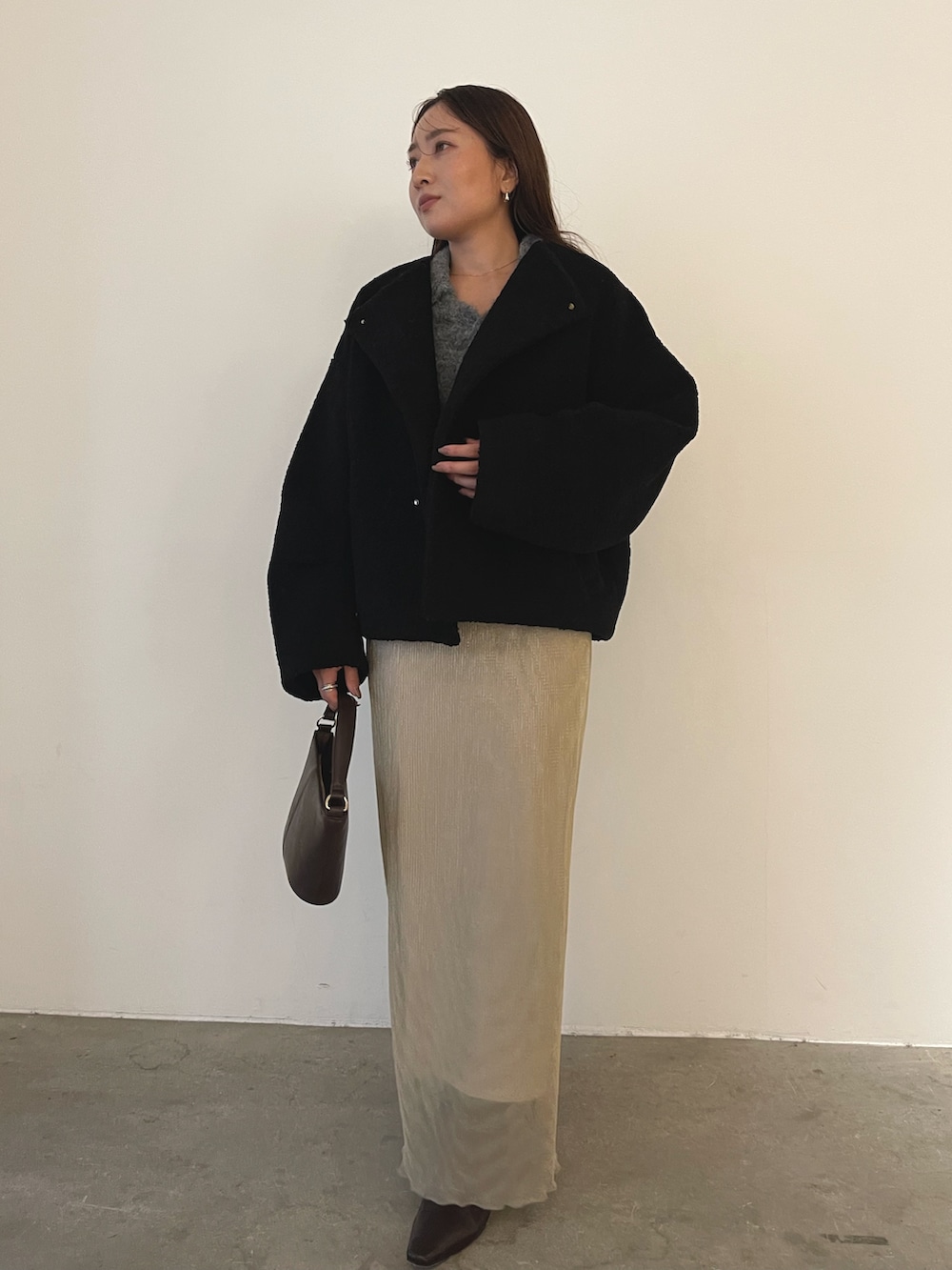 ブラック系のブルゾン、ブラウン系のハンドバッグ、ブラウン系のブーツを着用したレディースの秋コーディネートの3枚目の写真