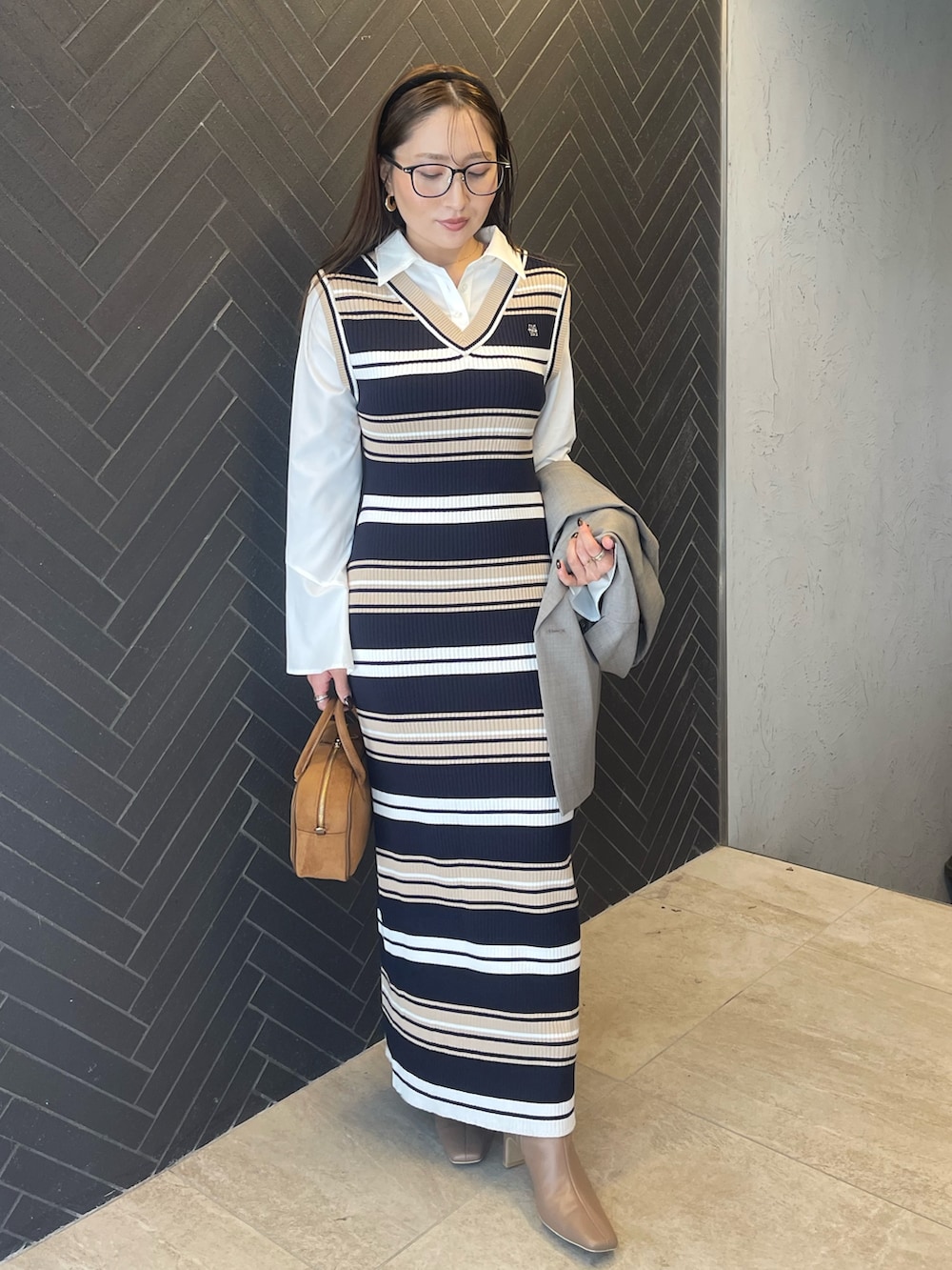 イエロー系のハンドバッグ、ベージュ系のブーツ、グレー系のテーラードジャケットを着用したレディースの冬コーディネートの3枚目の写真